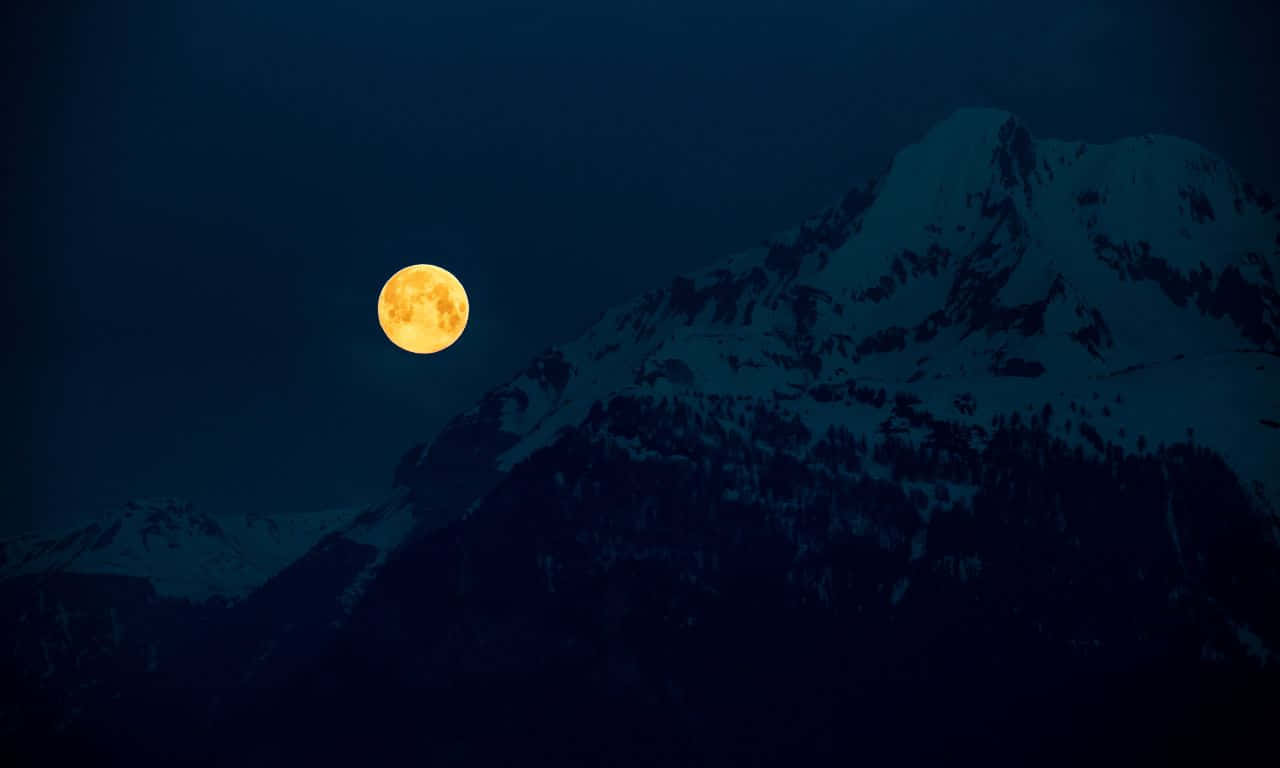 1280x768 桌布 壁紙 — 一輪明亮的滿月在深藍色夜空下照耀著積雪的山脈。