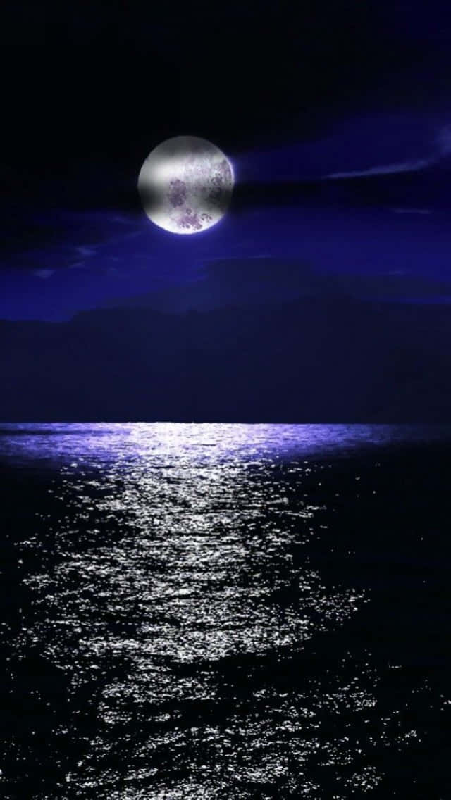 Moon iPhone 桌布 壁紙 — 一輪明亮的滿月在深藍色夜空下的黑暗海洋上投射出一條閃爍的銀色路徑。
