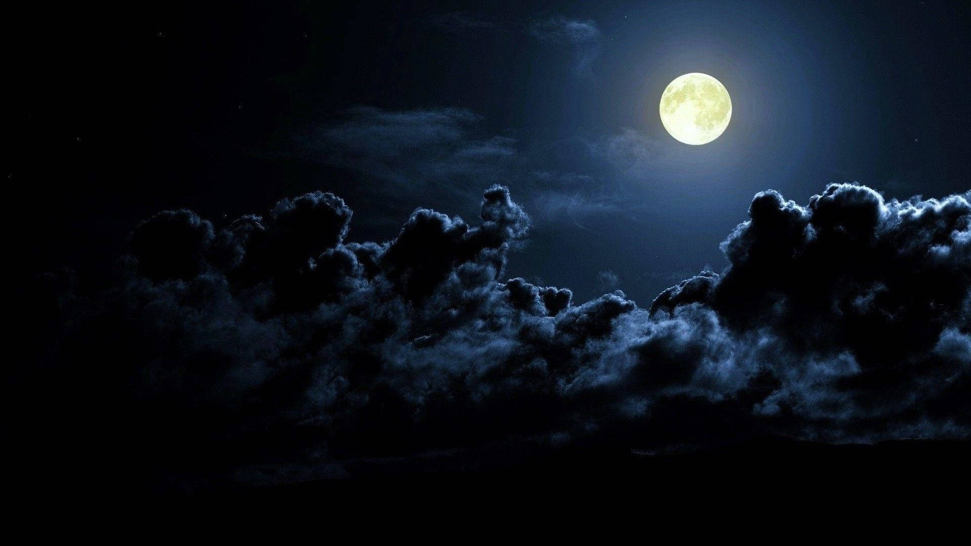 月亮桌面 桌布 壁紙 — 一輪明亮的滿月在深邃的夜空中穿過戲劇性的烏雲閃耀。