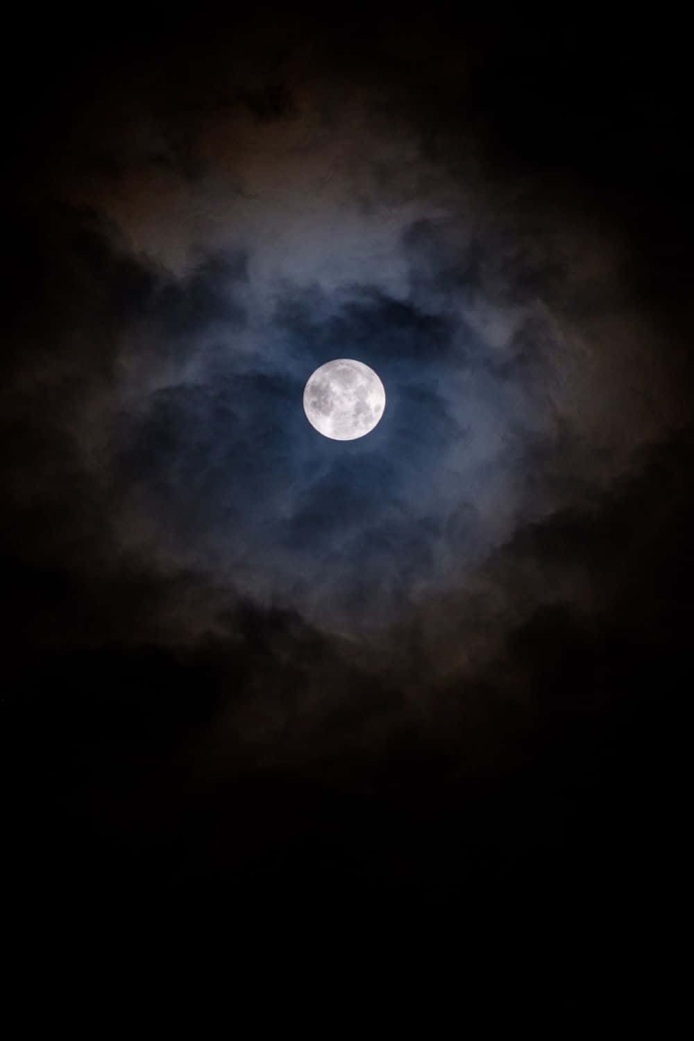 full moon 桌布 壁紙 — 一輪明亮的滿月在深邃的夜空中穿過旋轉的烏雲閃耀。