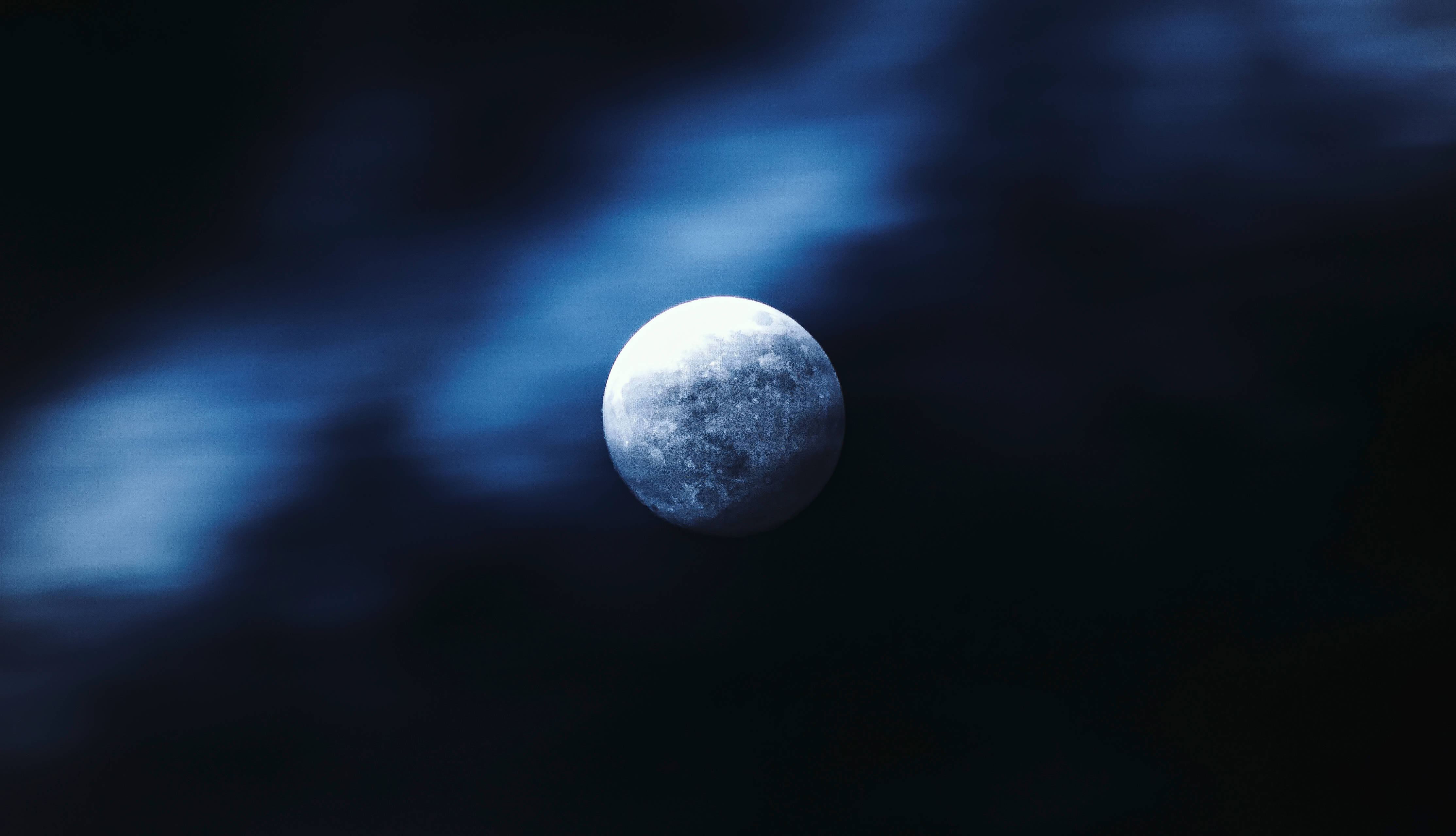 Dim 桌布 壁紙 — 一輪明亮的滿月在深邃的夜空透過旋轉的深藍色雲層發光。