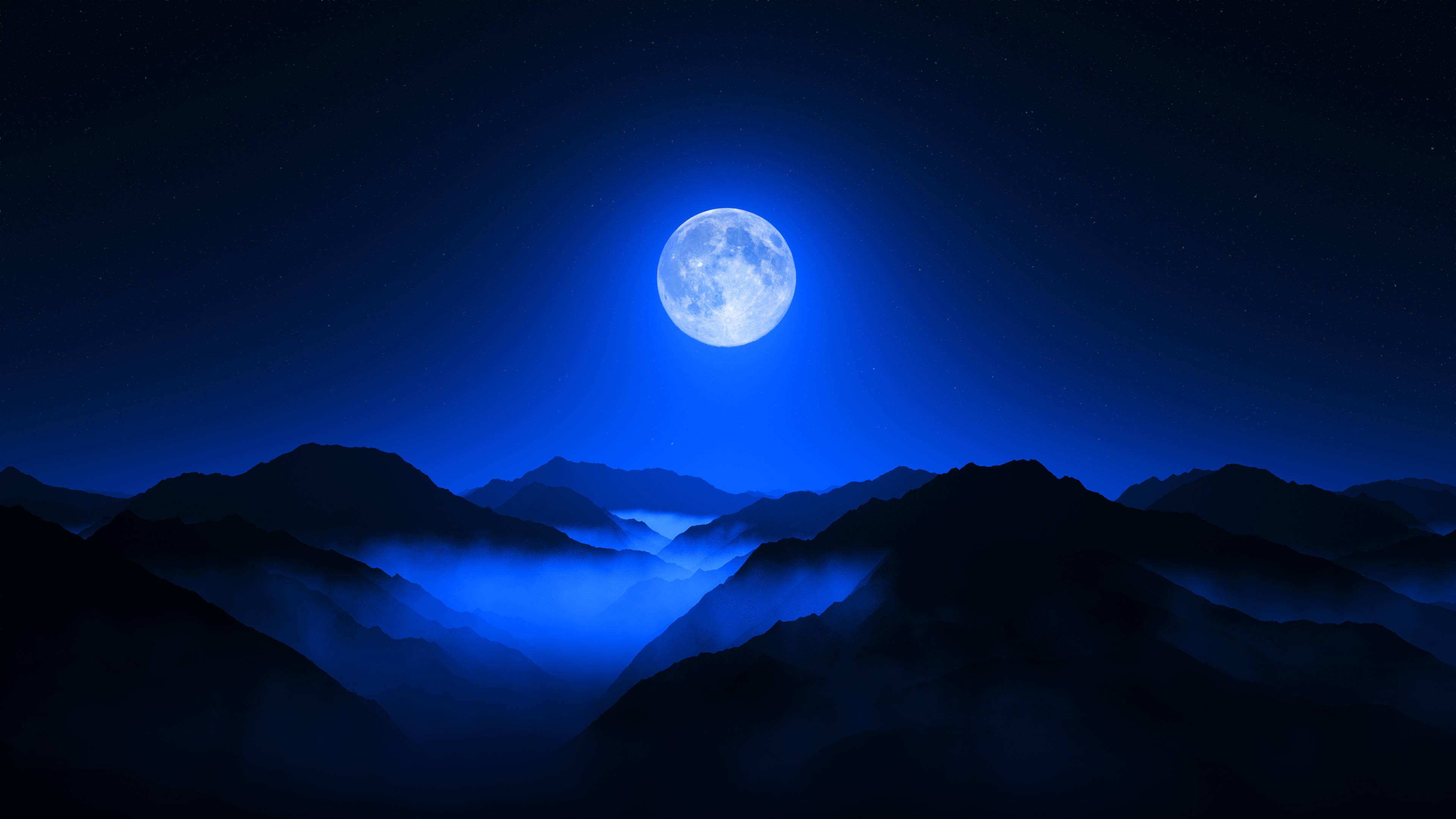 美學月亮 桌布 壁紙 — 一輪明亮的滿月在繁星點點的夜空下，將冷藍色的光芒投射在籠罩於霧氣山谷中的剪影山峰上。