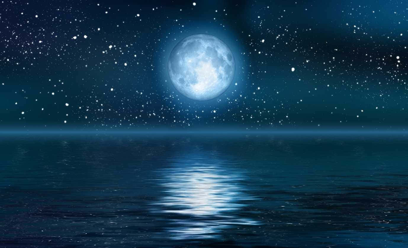 月亮與星星 桌布 壁紙 — 一輪明亮的滿月在繁星點點的夜空下，在平靜的海洋上投射出寧靜的光芒。