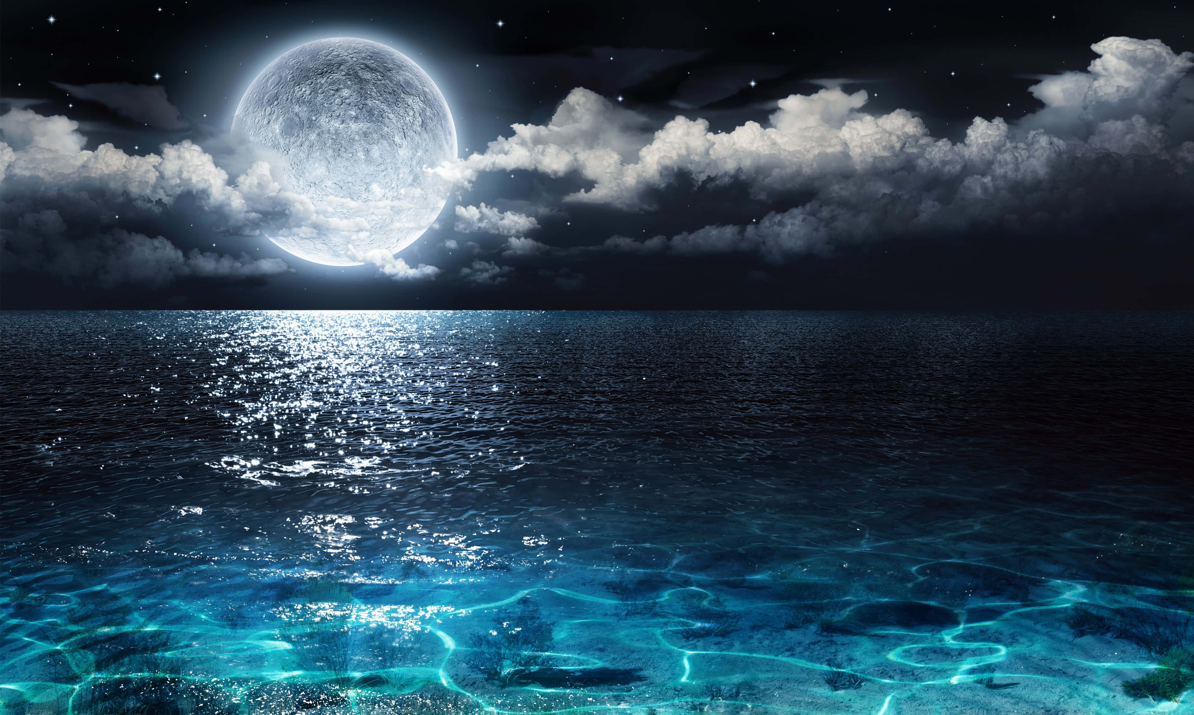 Moon Night 桌布 壁紙 — 一輪明亮的滿月在繁星點點的夜空和飄動的雲層下，將閃爍的藍光投射在平靜的海洋上。