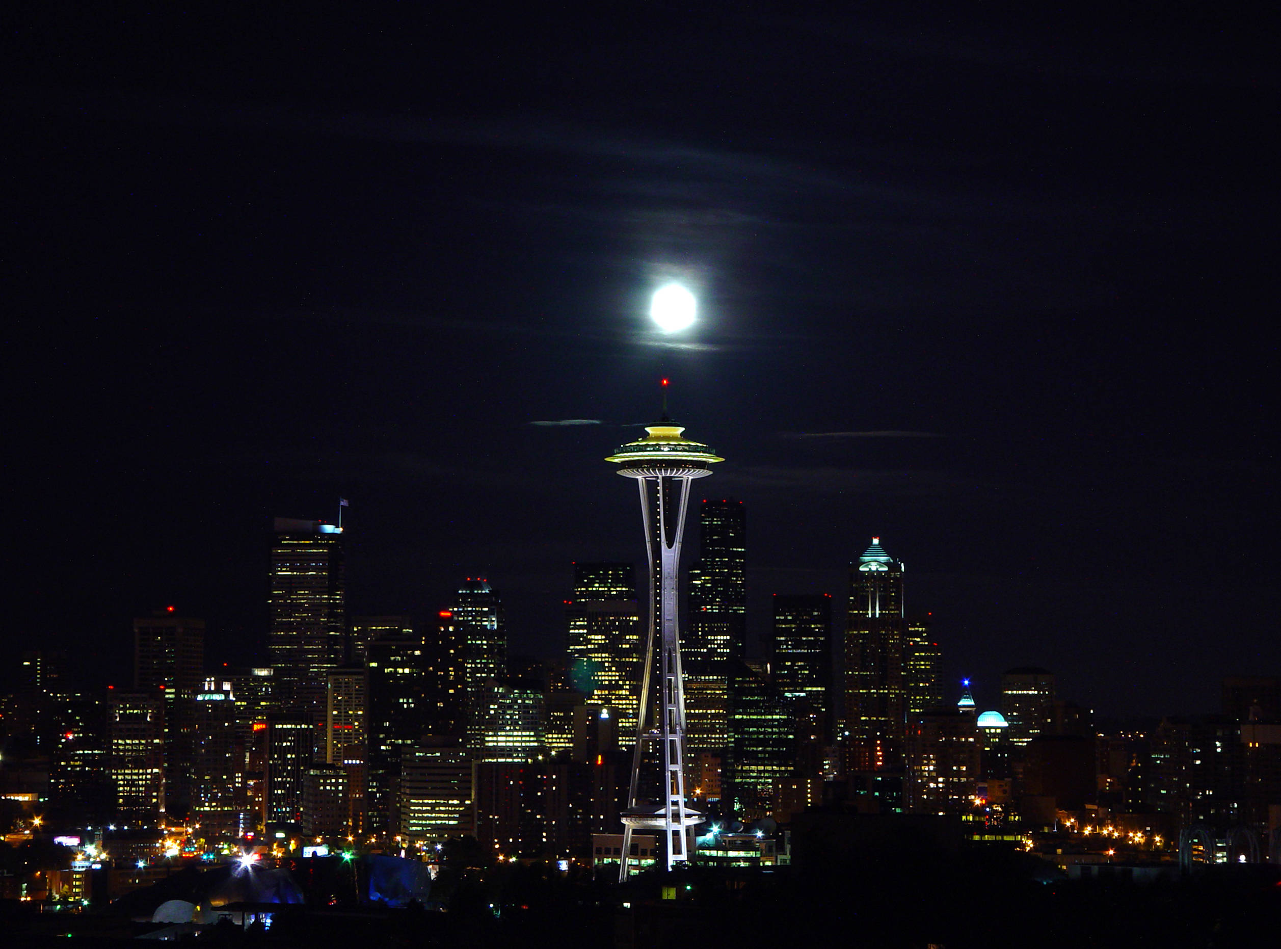 Seattle Skyline 桌布 壁紙 — 一輪明亮的滿月照亮了西雅圖的夜景，太空針塔在烏雲中閃耀。