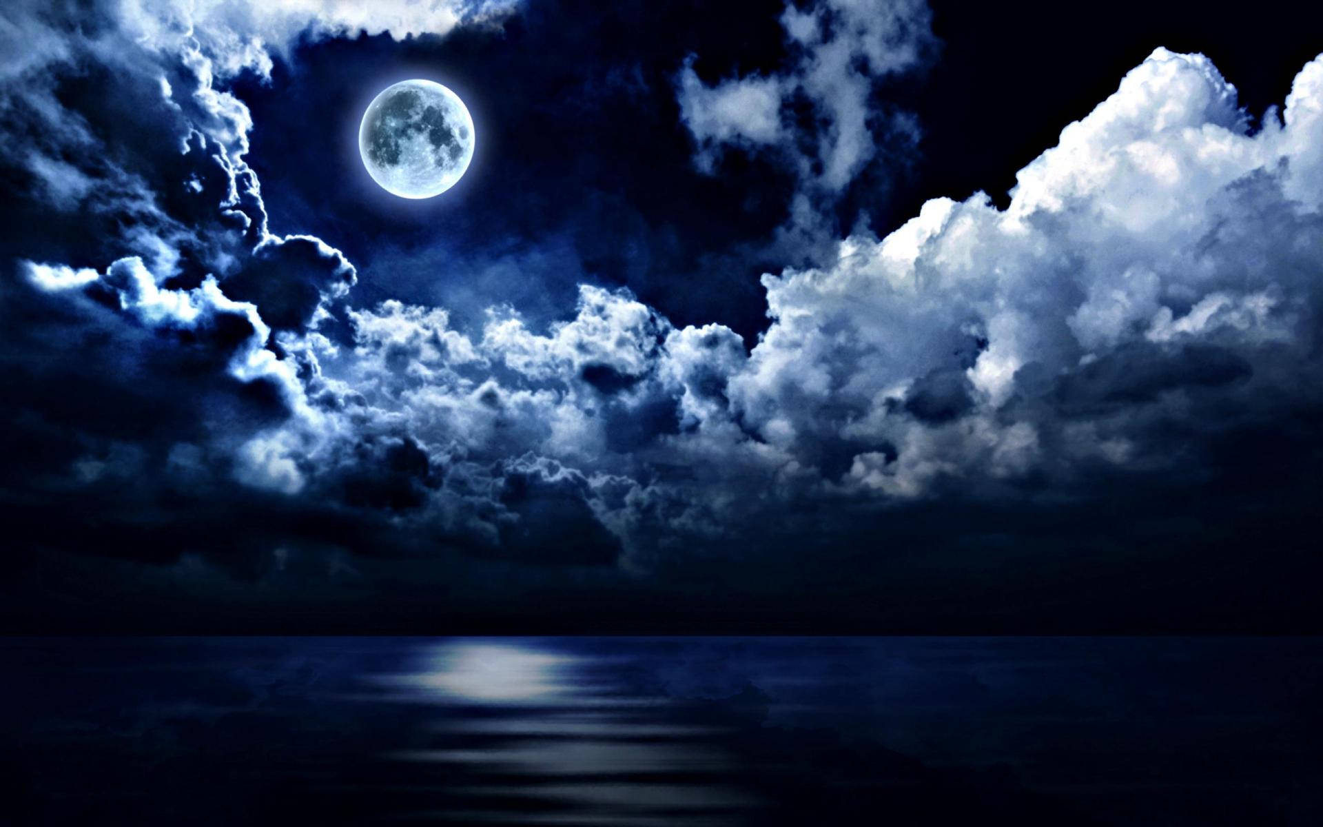 夜空 桌布 壁紙 — 一輪明亮的滿月穿透戲劇性的暴風雲，在下方平靜的海洋上投射出空靈的藍光。