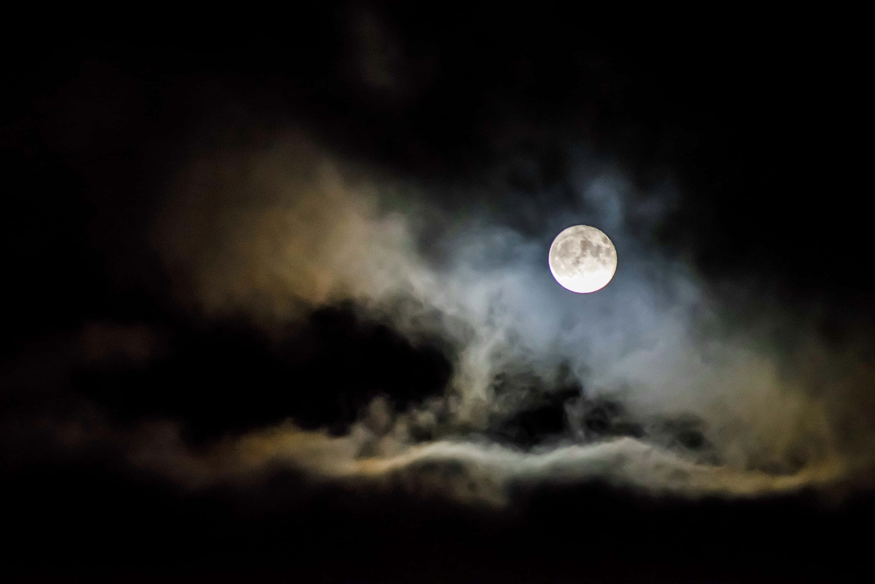 月光 桌布 壁紙 — 一輪明亮的滿月穿透旋轉的烏雲，在陰鬱的夜空中閃耀。