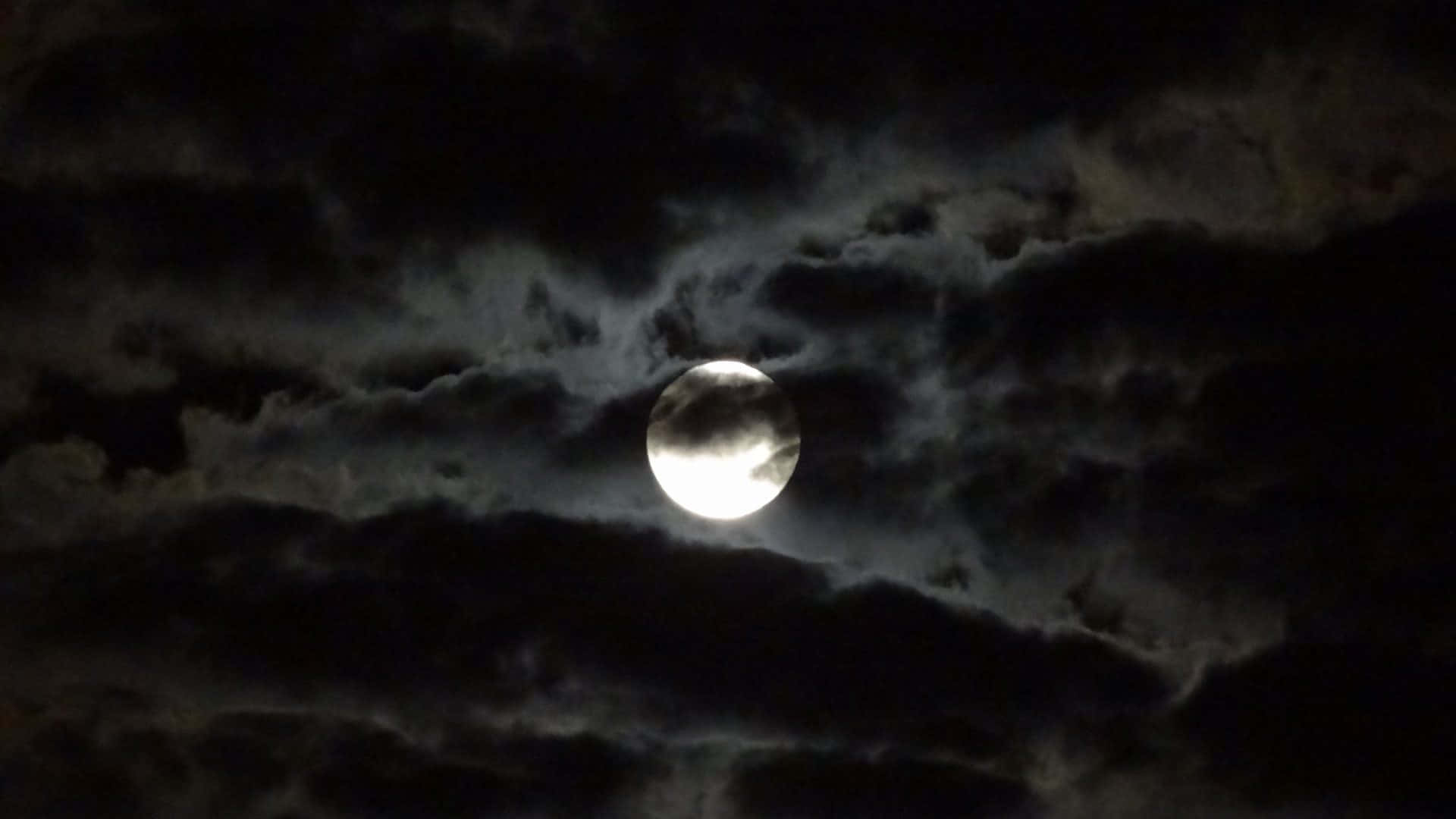 雲朵 桌布 壁紙 — 一輪明亮的滿月穿透濃密的烏雲，在戲劇性的夜空中閃耀。