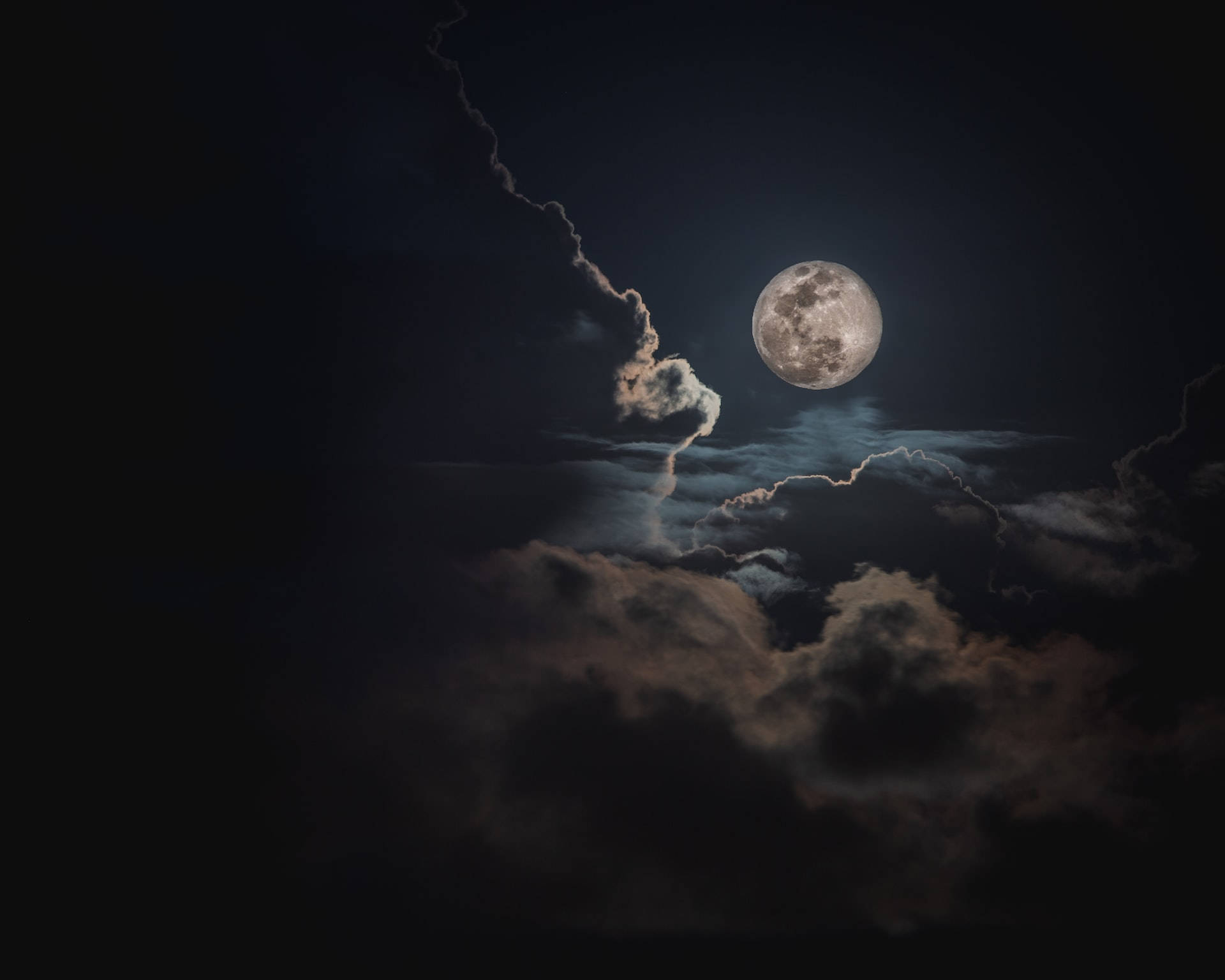 月光 桌布 壁紙 — 一輪明亮的滿月穿過戲劇性的烏雲，在陰沉的夜空中閃耀。