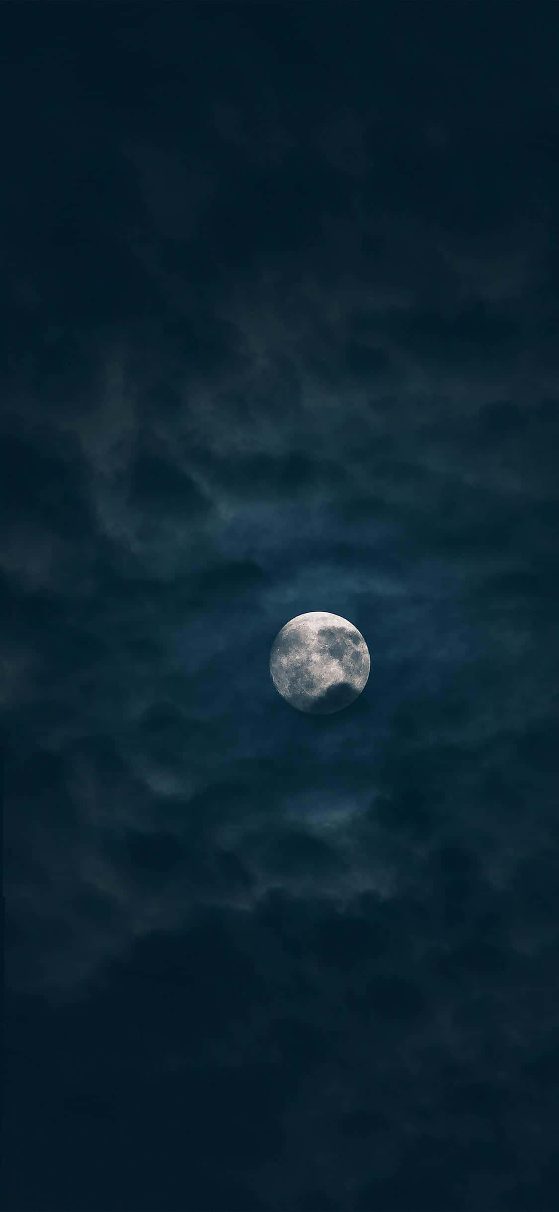 月夜星空 桌布 壁紙 — 一輪明亮的滿月穿過旋轉的烏雲，在陰沉的夜空中發光。