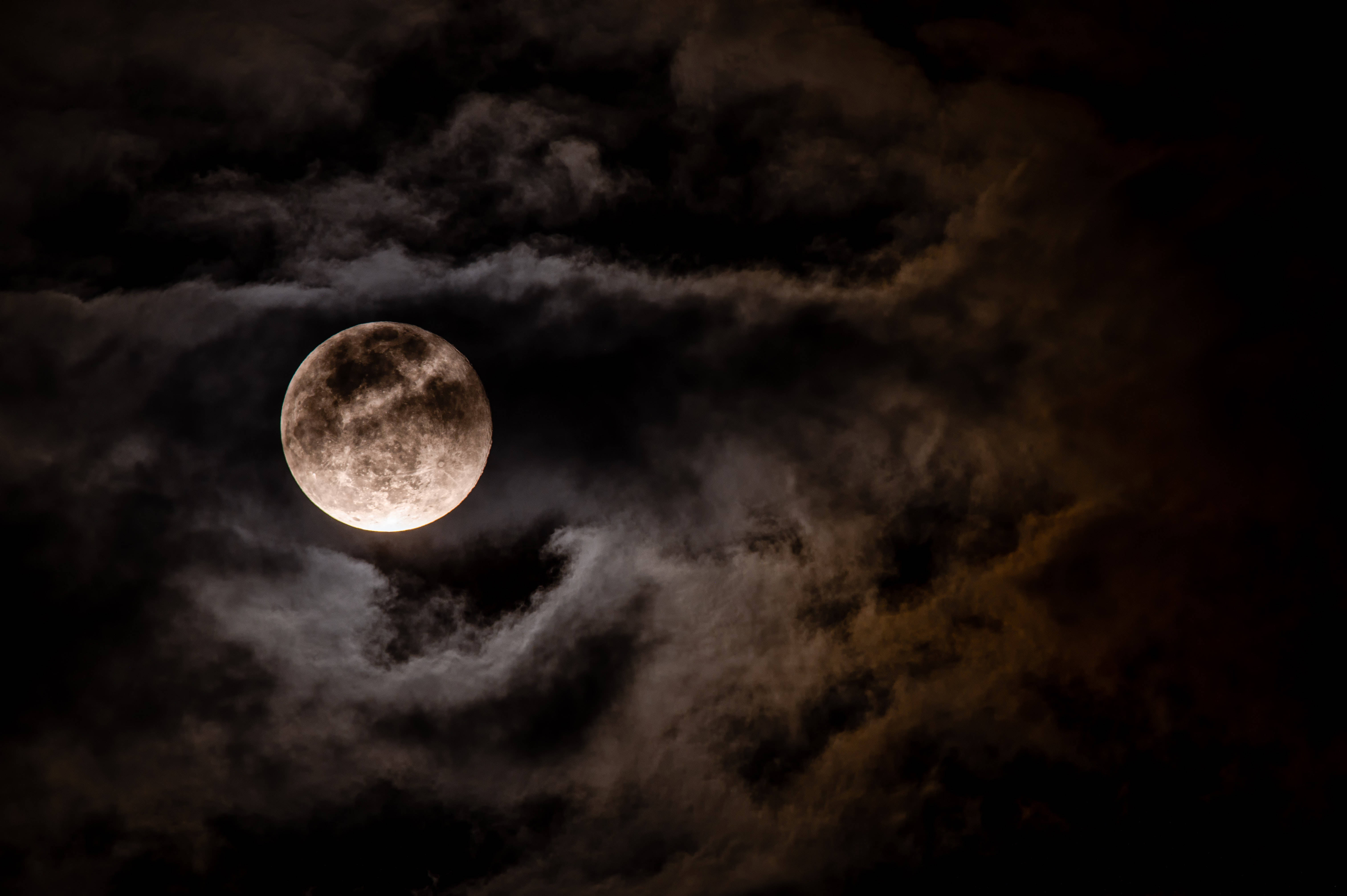 full moon 桌布 壁紙 — 一輪明亮的滿月穿過旋轉的烏雲，在戲劇性的夜空中閃耀。
