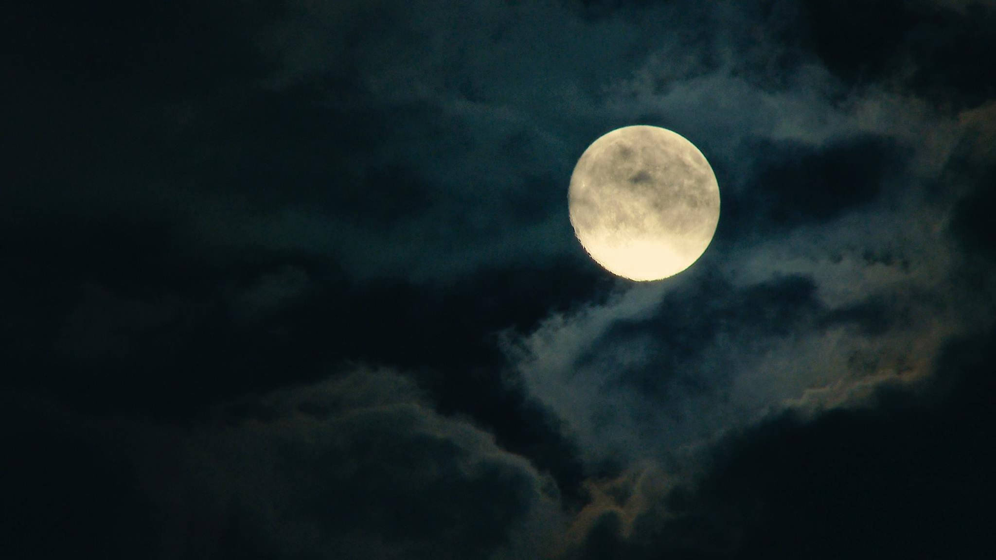 Beautiful Full Moon 桌布 壁紙 — 一輪明亮的滿月穿過旋轉的烏雲，在陰鬱的夜空中閃耀。