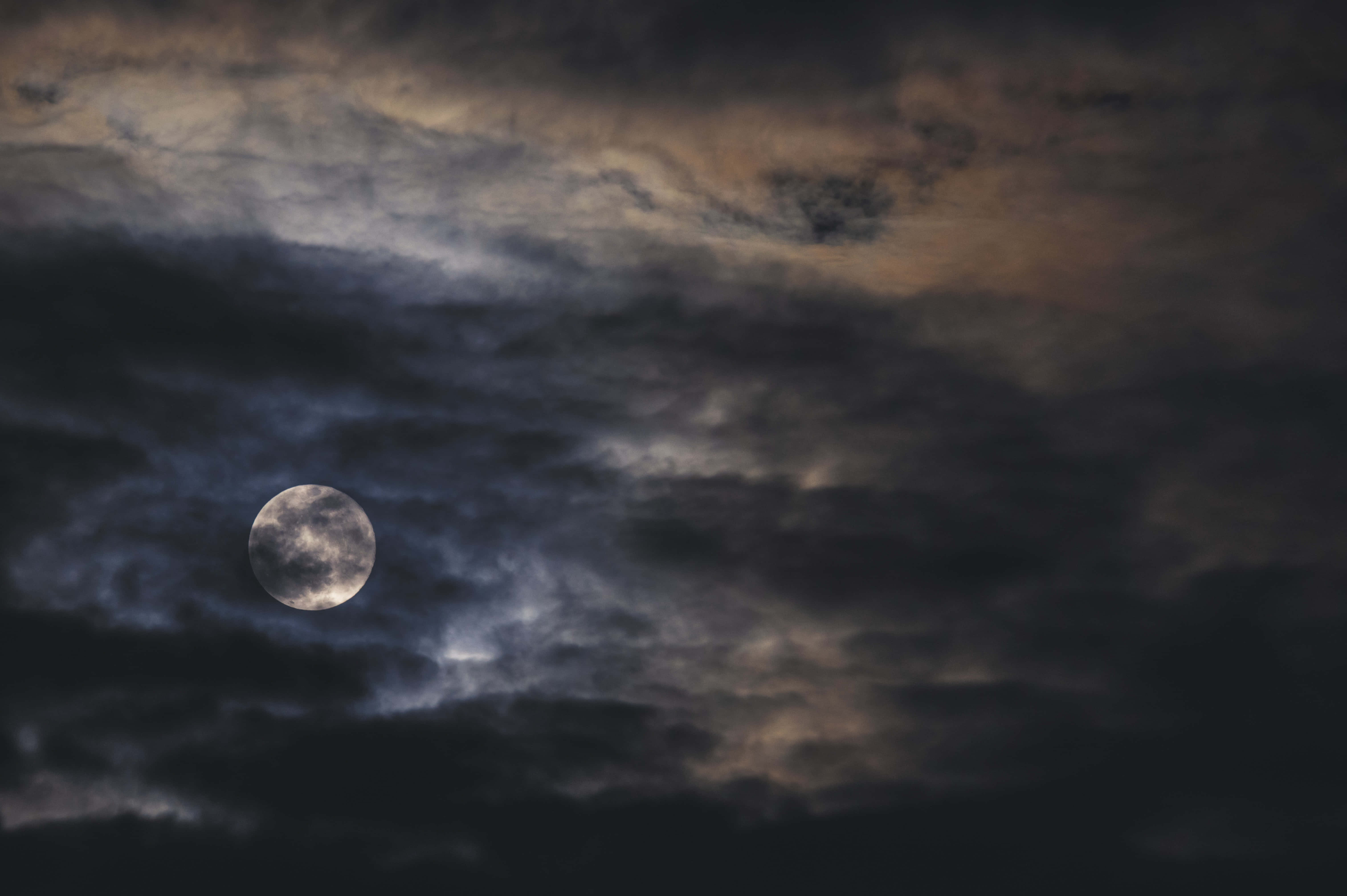 Dark Moon 桌布 壁紙 — 一輪明亮的滿月穿過旋轉的烏雲，在陰鬱的夜空中閃耀。