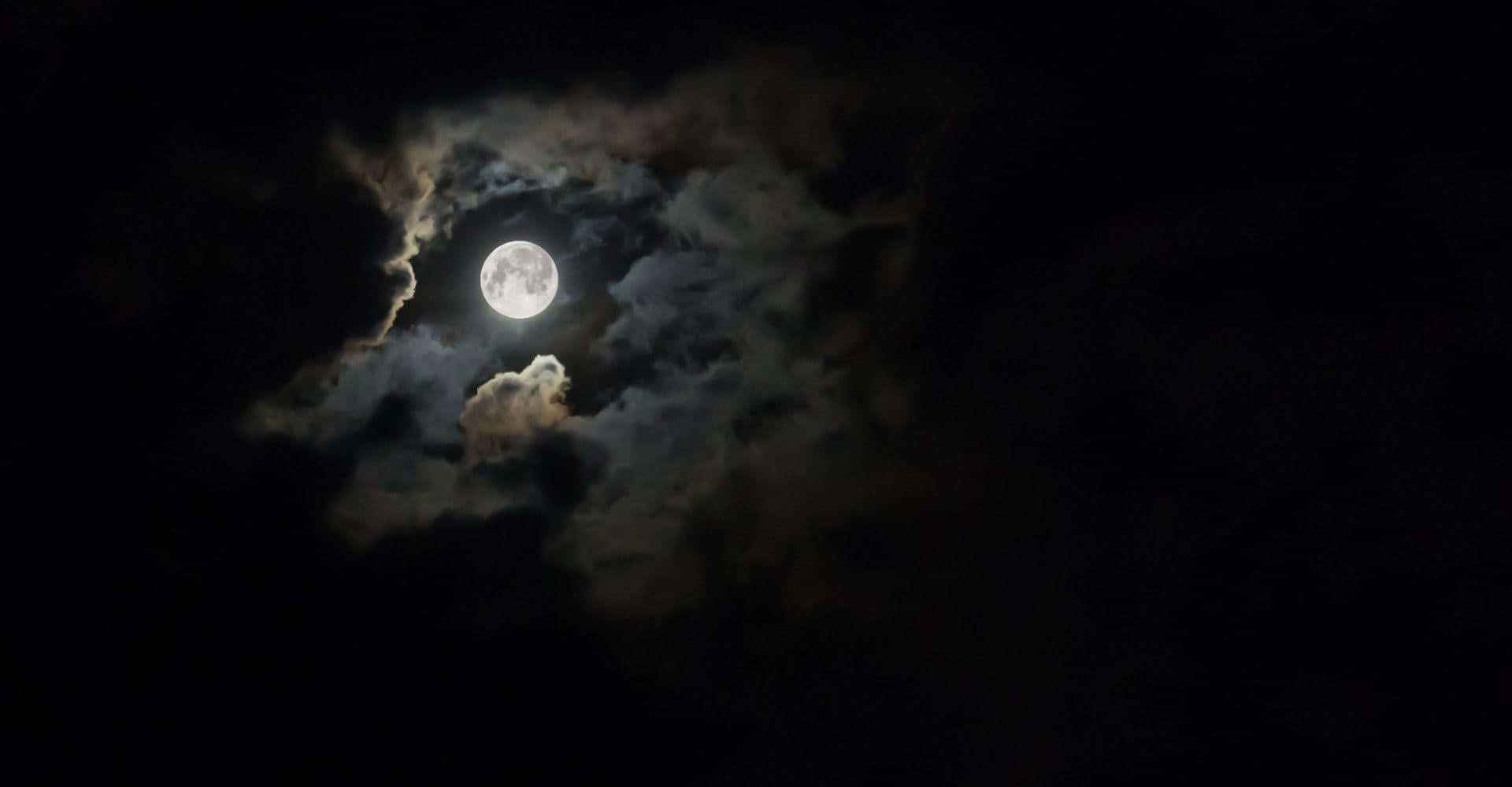 月光 桌布 壁紙 — 一輪明亮的滿月穿過薄雲，在漆黑的夜空中閃耀。