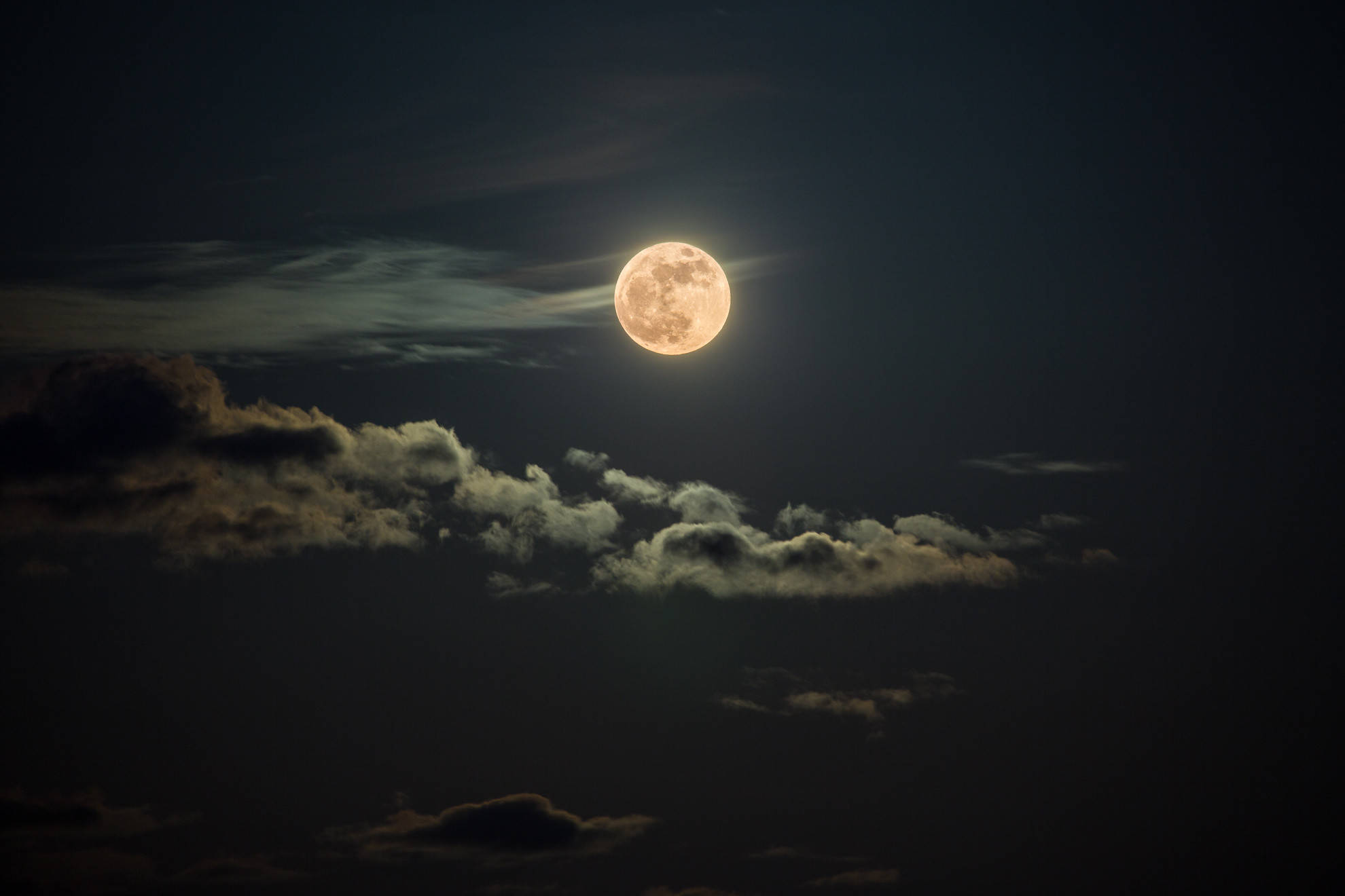 美學月亮 桌布 壁紙 — 一輪明亮的滿月透過散落的雲層在深邃的夜空中發光。