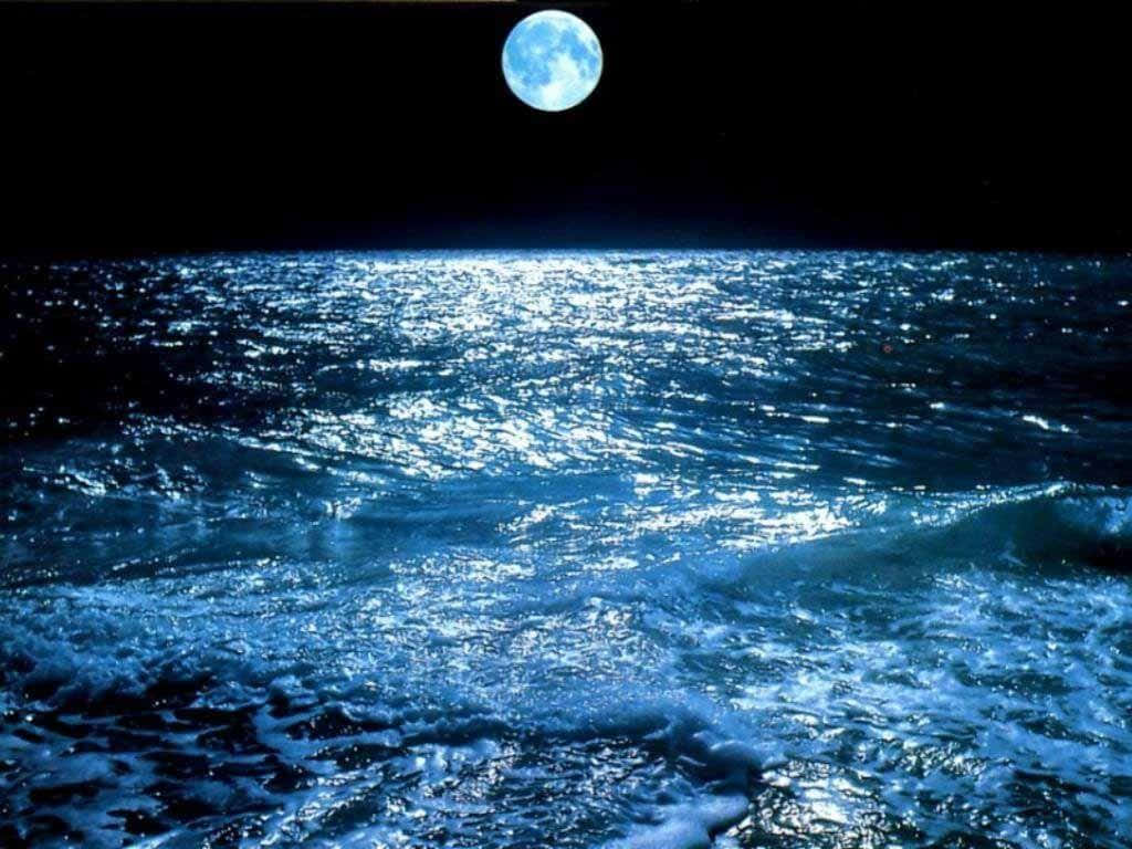 Moonlight 桌布 壁紙 — 一輪明亮的藍月在漆黑的夜空下，在波濤洶湧的海洋上投下閃爍的倒影。