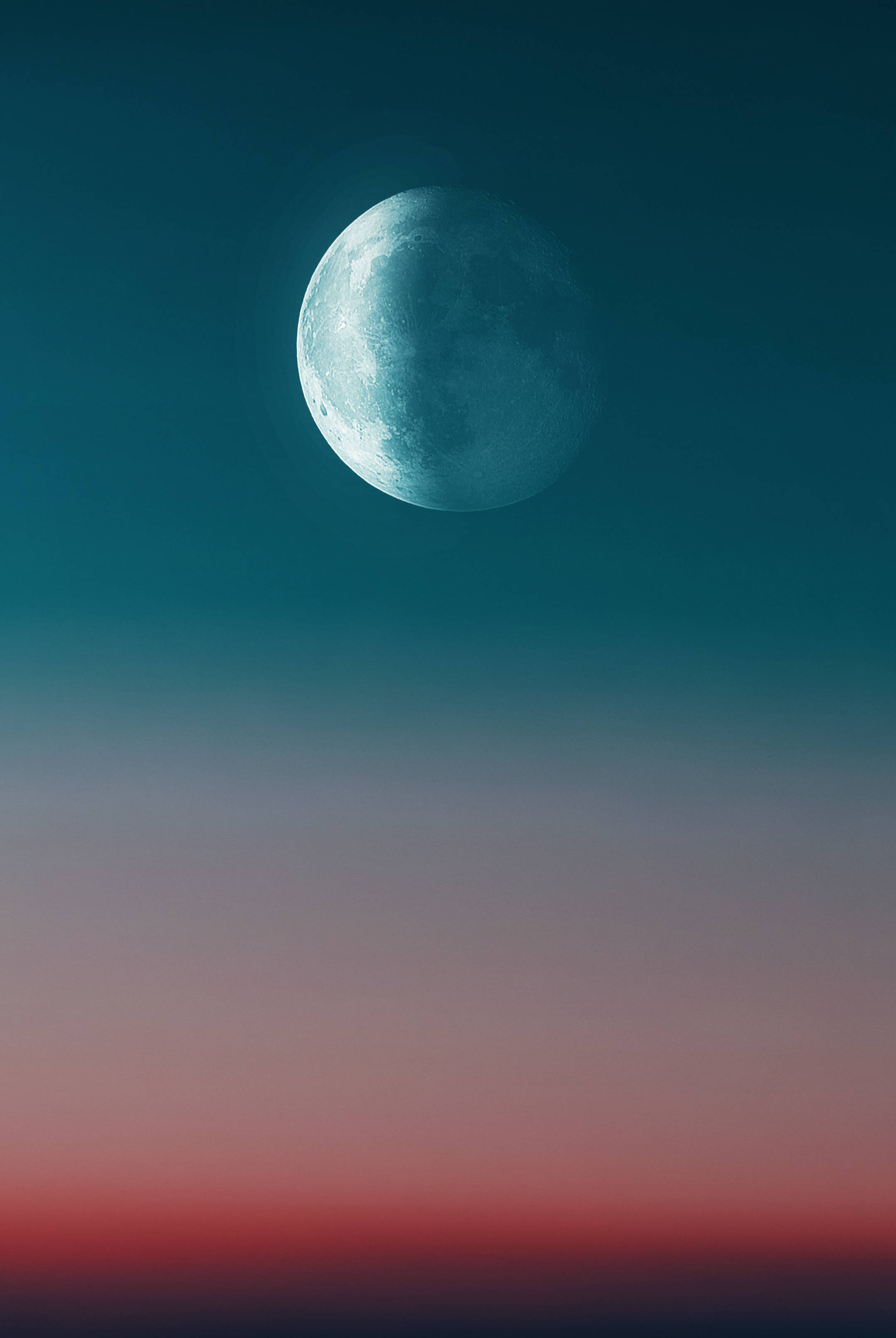 太空 桌布 壁紙 — 一輪明亮的藍月懸掛在暮色天空中，從藍綠色漸變到地平線附近的深紅色。