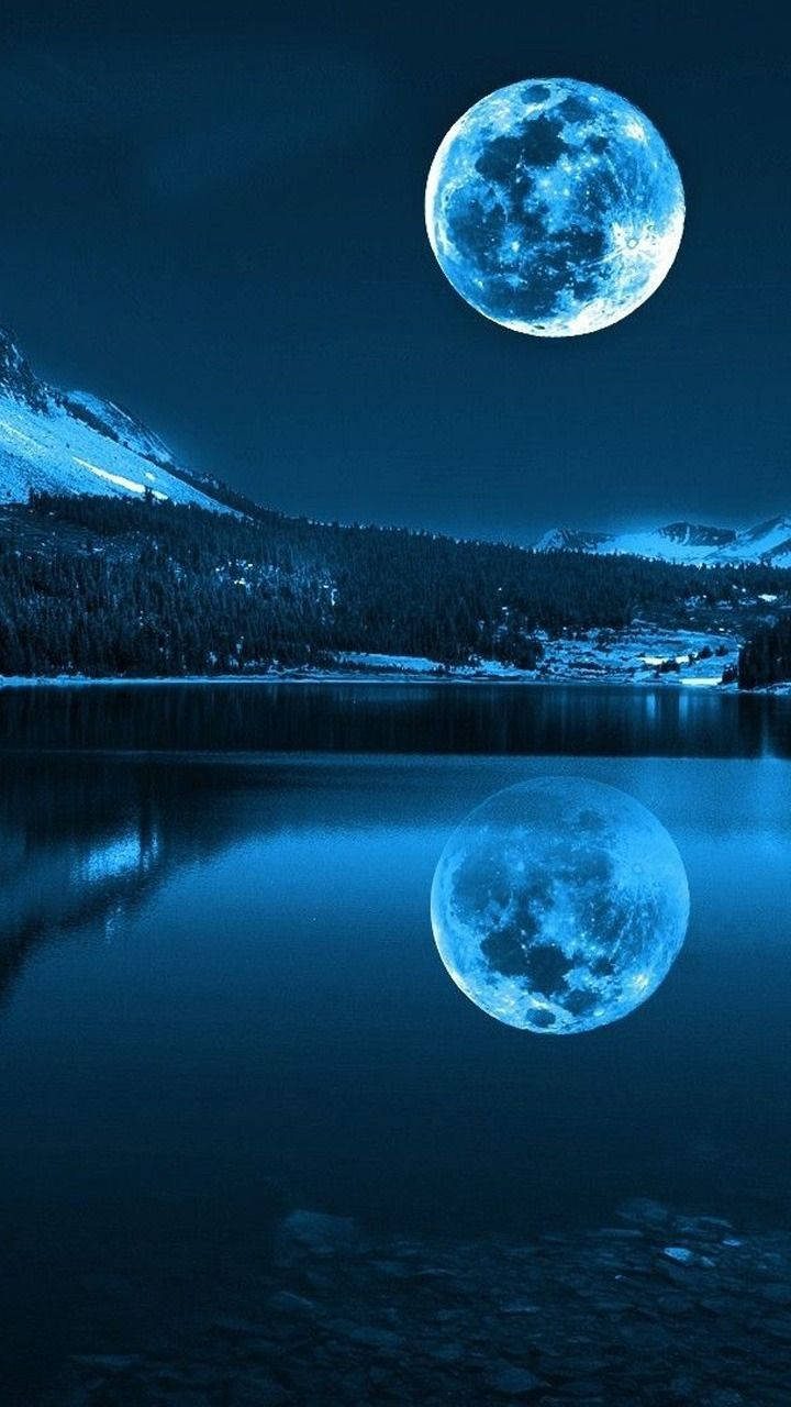 Moon Phone 桌布 壁紙 — 一輪明亮的藍月懸掛在積雪的山湖上空，在漆黑的夜空下完美倒映在平靜的水面上。