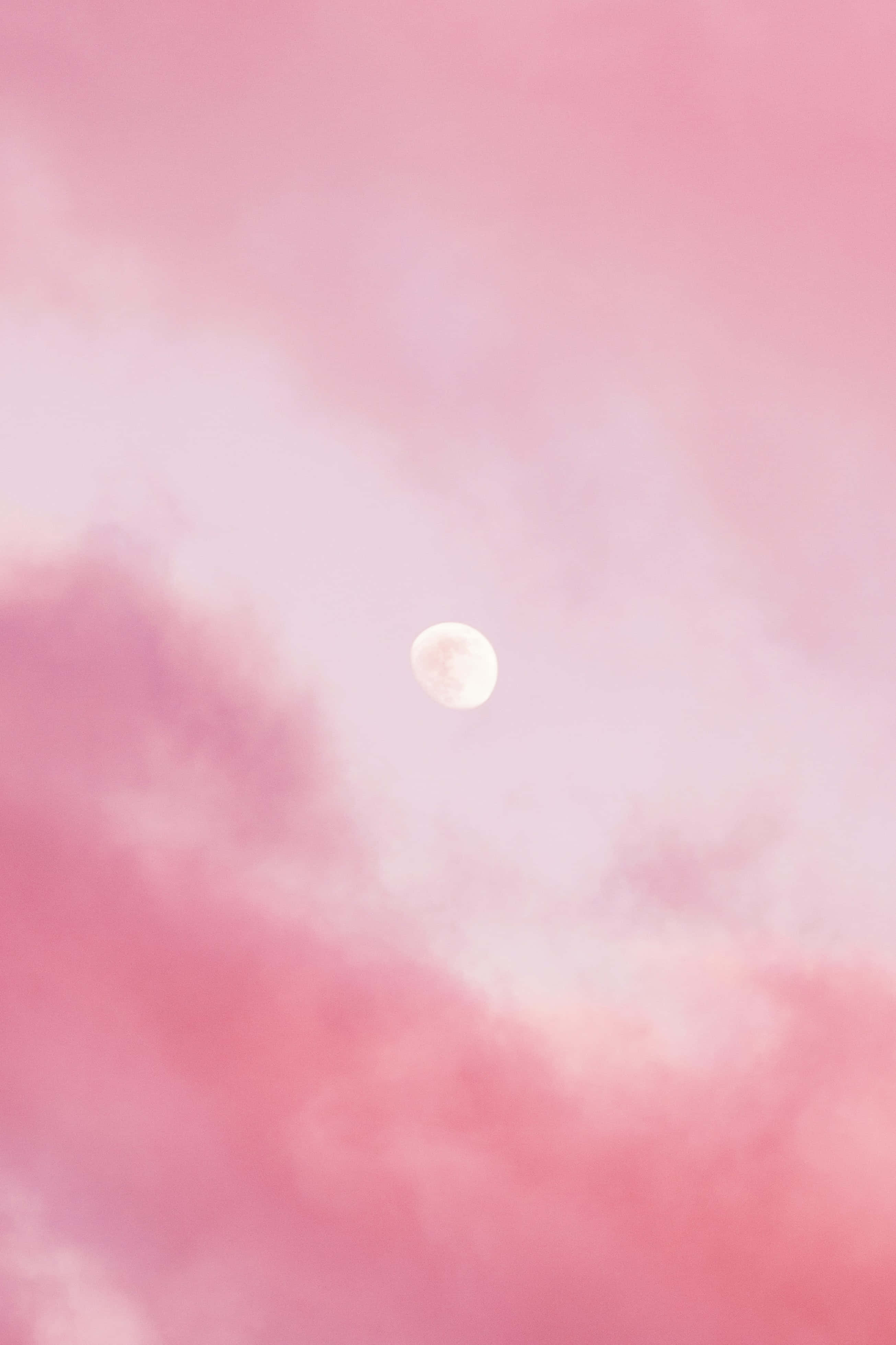 Pink Sky 桌布 壁紙 — 一輪柔和發光的月亮漂浮在夢幻般的粉紅雲朵中，寧靜的暮色天空。