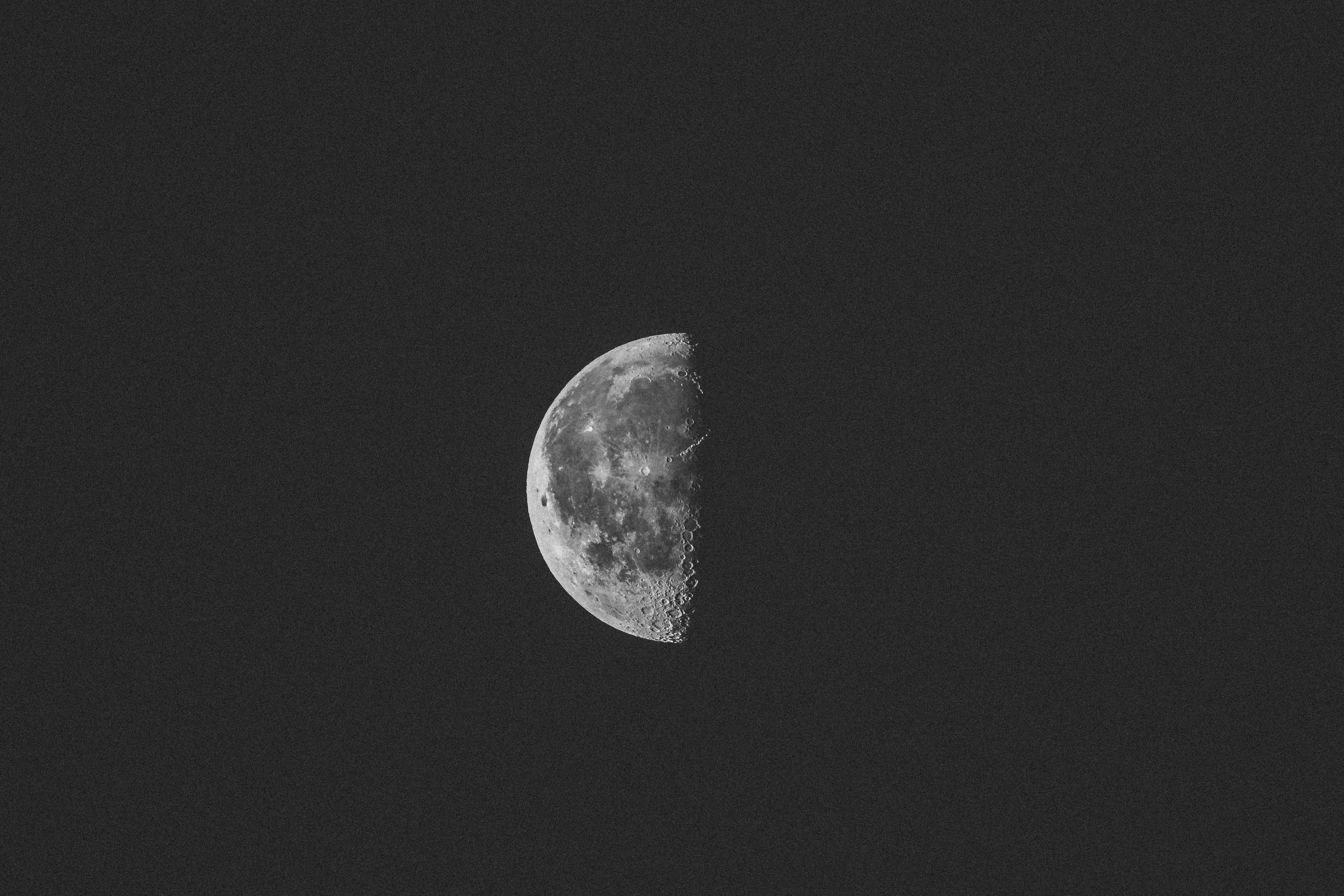 夜空 桌布 壁紙 — 一輪清晰的灰階半月掛在深邃的黑色天空中，顯露出隕石坑和崎嶇的地形。