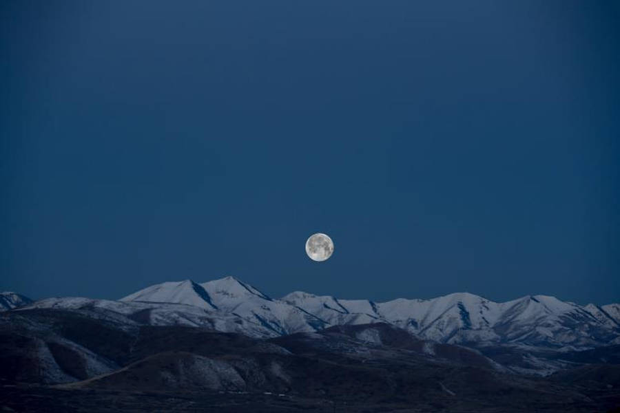 HD Moon 桌布 壁紙 — 一輪滿月在深藍色暮色天空下照耀著積雪覆蓋的山脈。