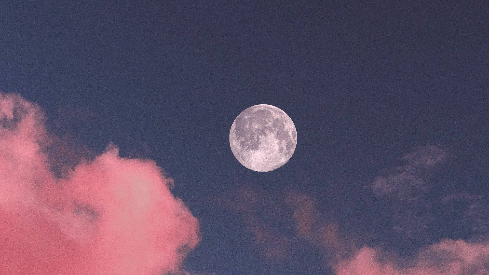 月光 桌布 壁紙 — 一輪滿月在深藍色的天空中寧靜地發光，天空點綴著柔和的粉紅色雲彩。