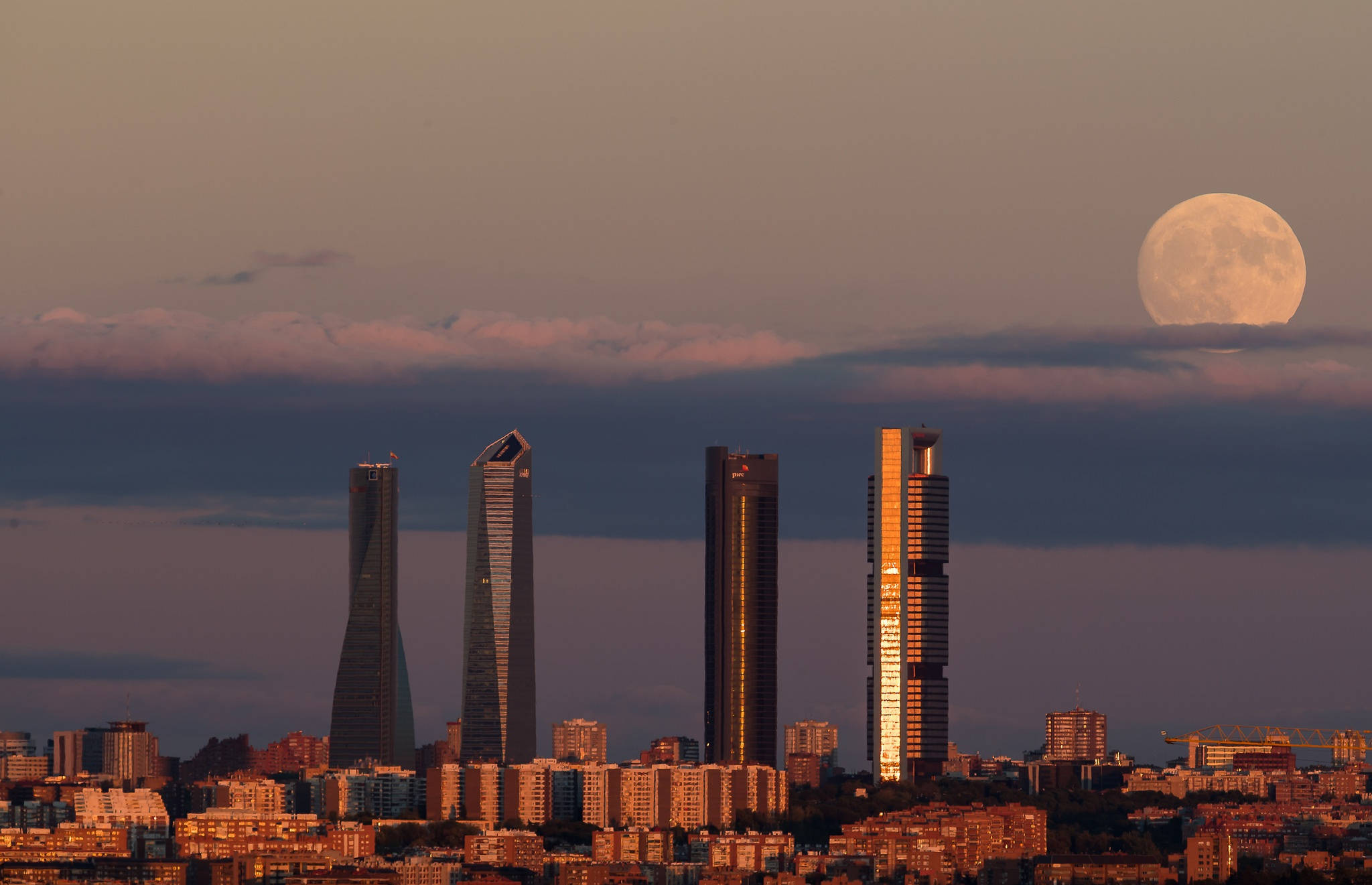 Madrid 桌布 壁紙 — 一輪滿月在雲層後升起，照耀著沐浴在金色暮光中的馬德里標誌性摩天大樓。