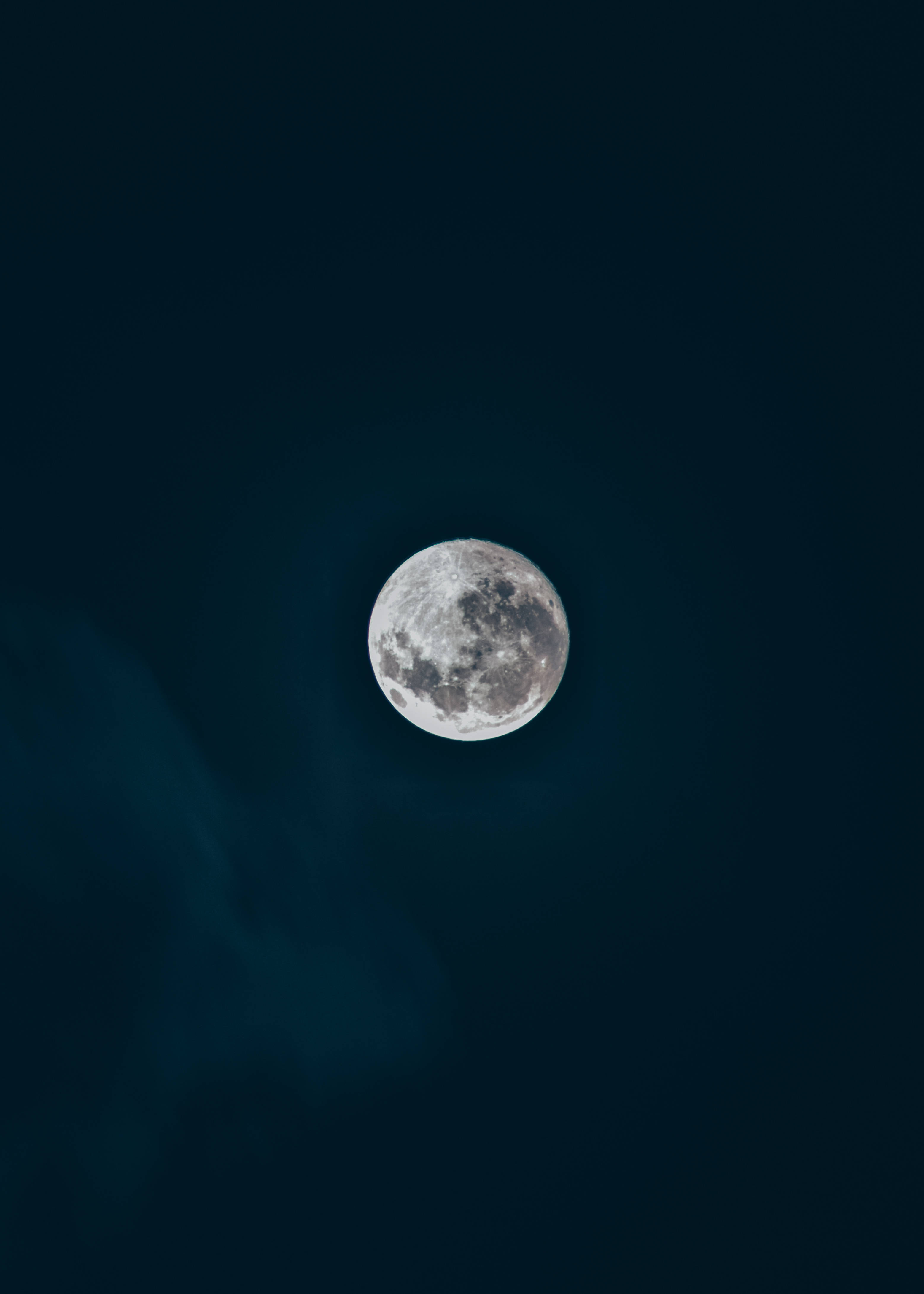 Beautiful Full Moon 桌布 壁紙 — 一輪滿月柔和地發光，映襯著深靛藍色的夜空，薄雲飄過。