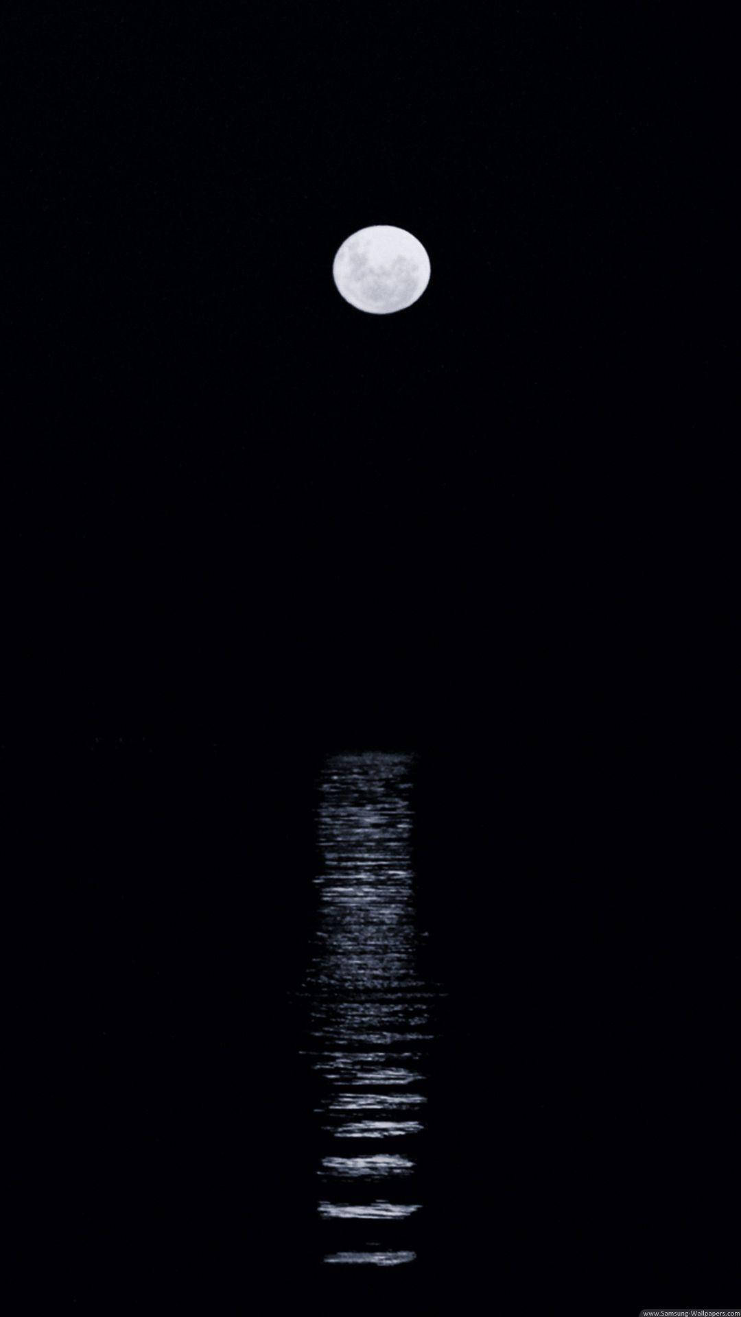 Night Sky Moon 桌布 壁紙 — 一輪滿月靜靜懸掛在漆黑的天空中，其發光的倒影在黑暗的水面上垂直閃爍。