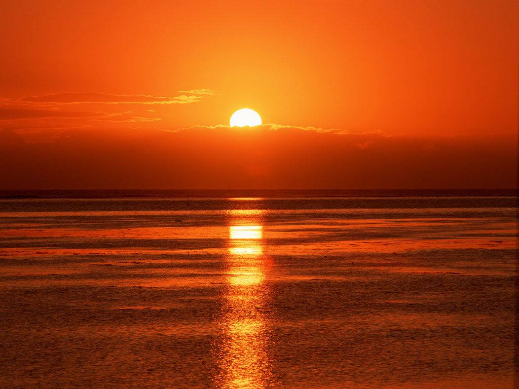 旭日東昇 桌布 壁紙 — 一輪熾熱的橙色夕陽在平靜的水面上落下，在漣漪的水面投下燦爛的倒影。