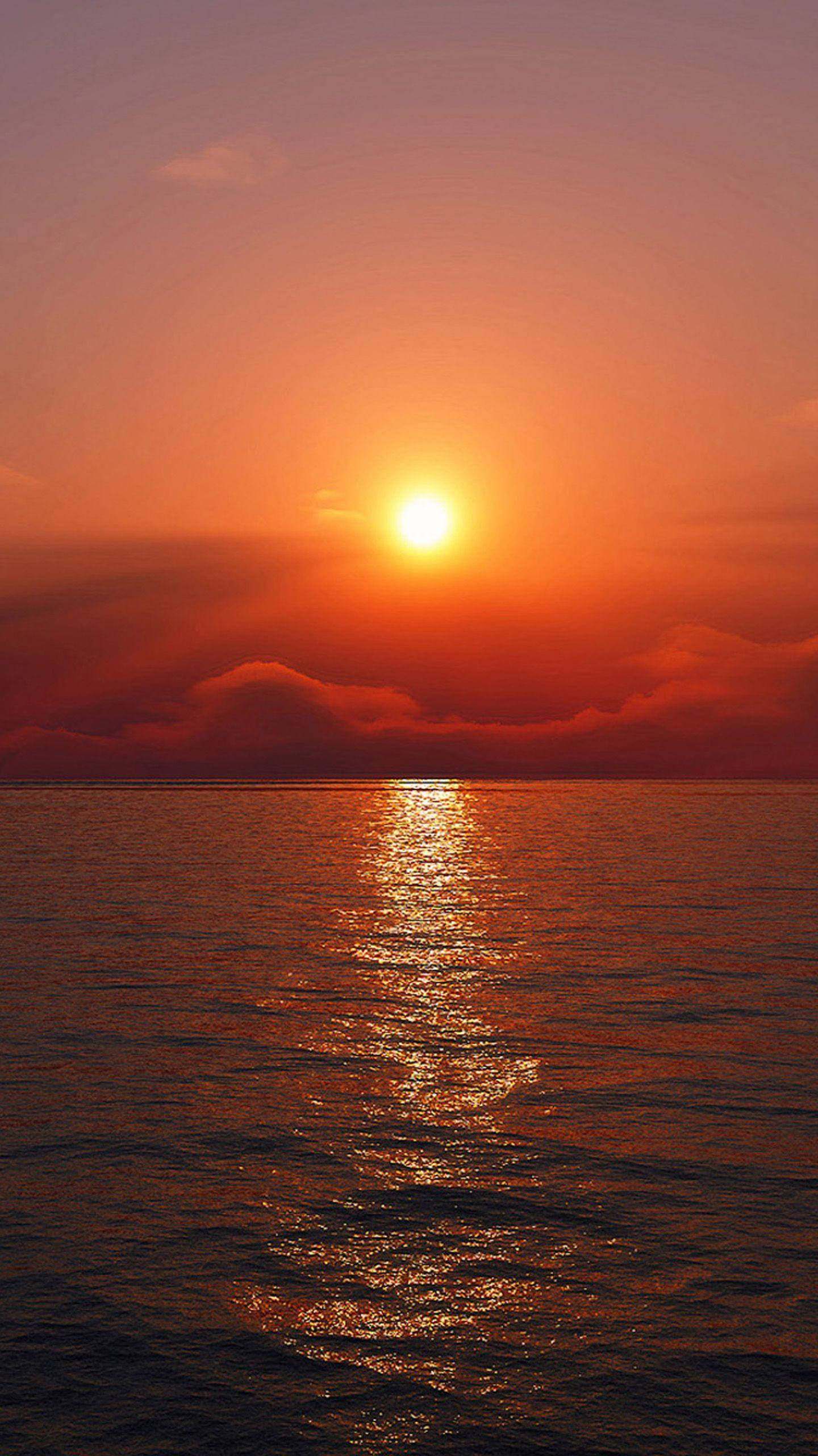 quiet 桌布 壁紙 — 一輪燦爛的太陽在平靜的海面上落下，在天空中投下火熱的橙色和紅色色調，並在溫柔的波浪上反射出閃爍的光芒。