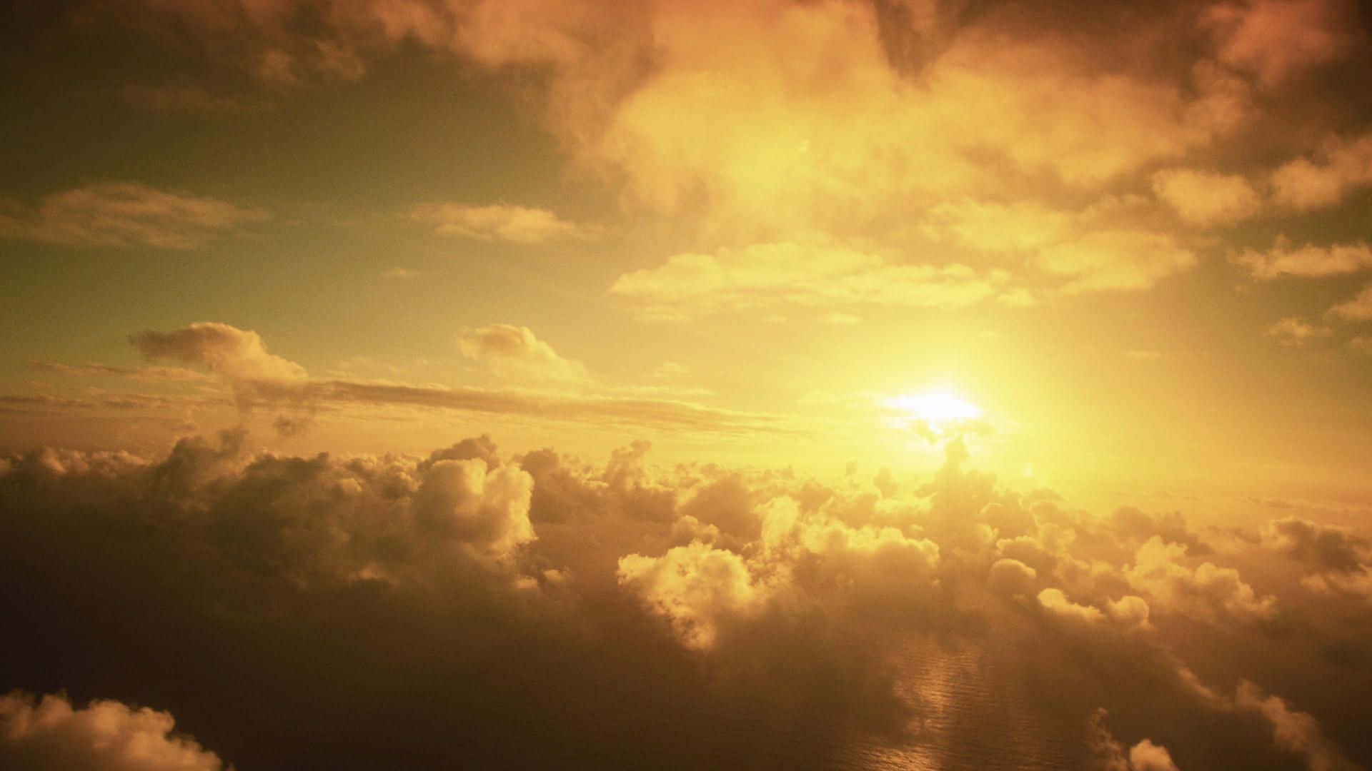 Yellow Sky 桌布 壁紙 — 一輪燦爛的太陽穿過金色雲層，將溫暖的光芒灑在下方廣闊的海洋上。
