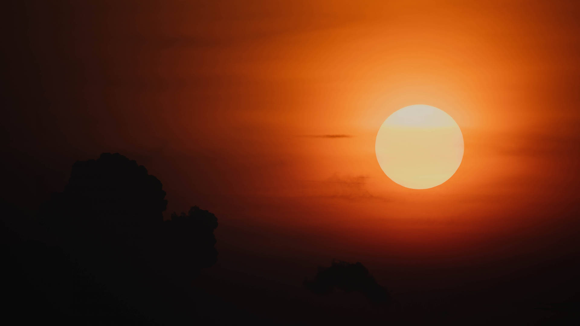 太陽 桌布 壁紙 — 一輪燦爛的橙色太陽在黑暗的雲影後落下，在天空中投射出溫暖的光芒。