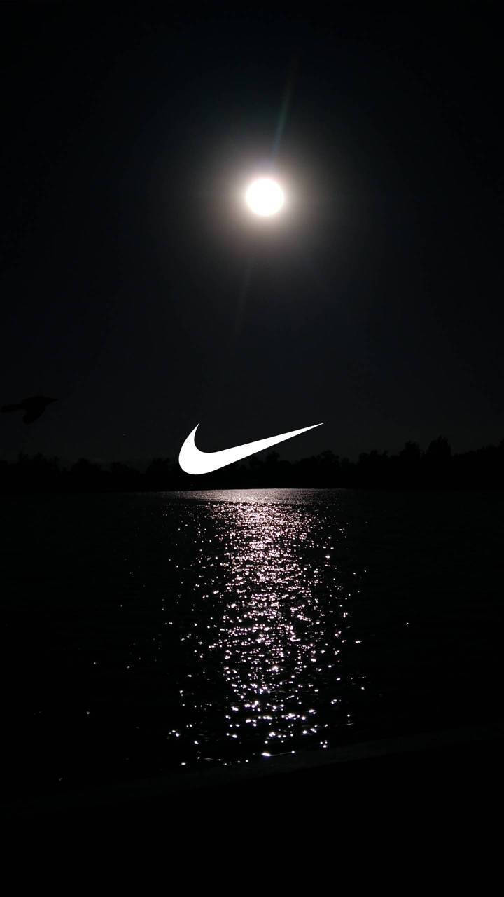 Swoosh 桌布 壁紙 — 一輪發光的月亮照亮黑暗的湖泊，一個白色Nike勾勾漂浮在閃爍的水面上。