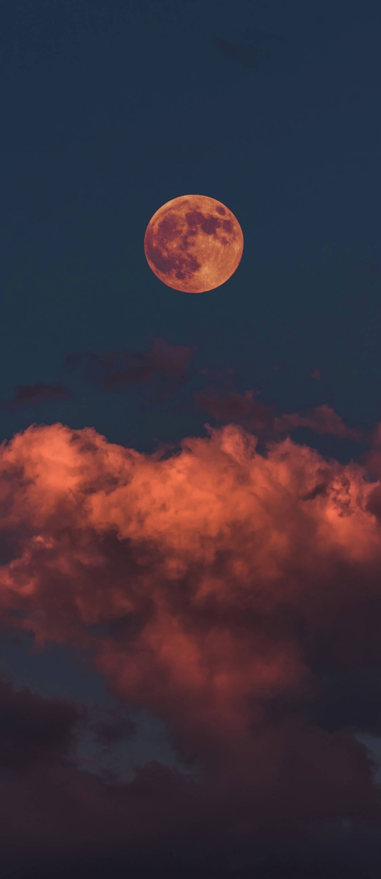 萬聖節 iPhone 桌布 壁紙 — 一輪發光的橙色滿月懸掛在火紅色的雲層之上，映襯著深藍色的暮色天空。