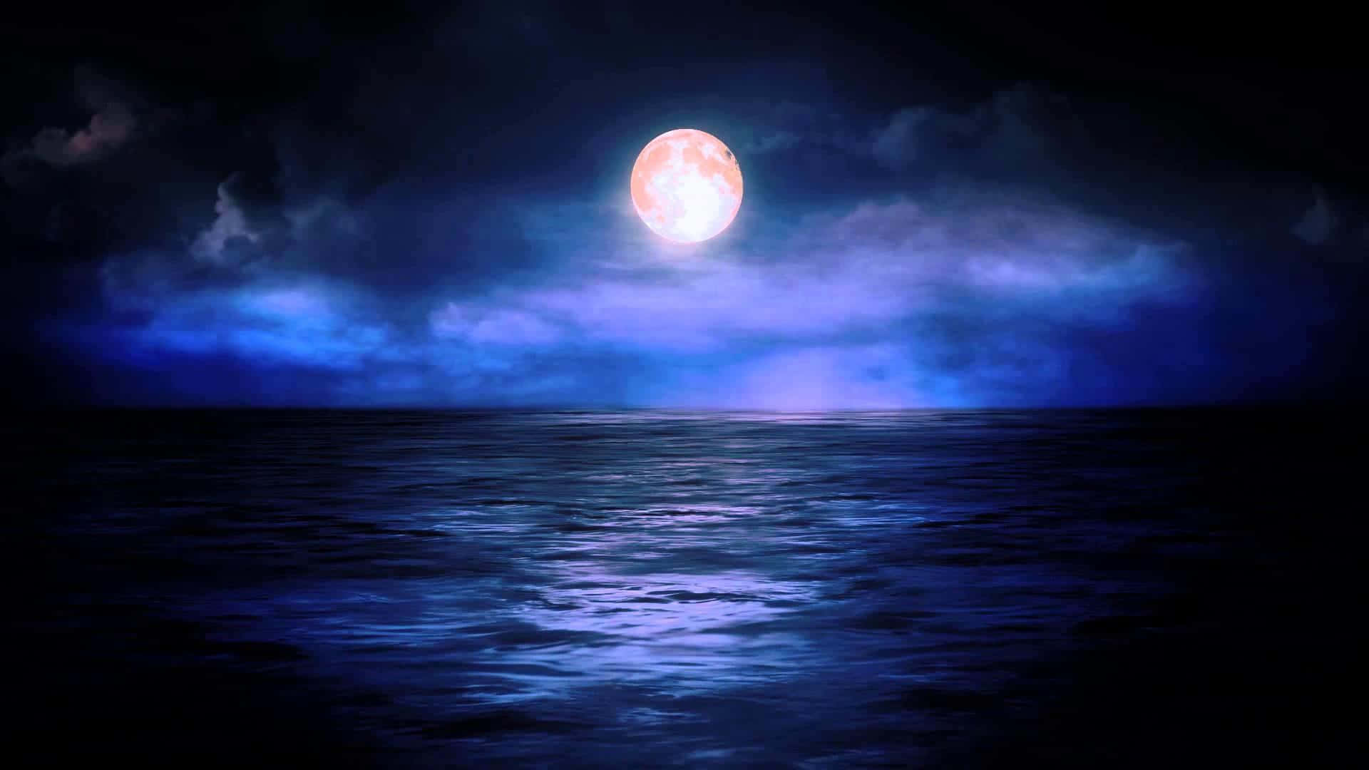 Midnight 桌布 壁紙 — 一輪發光的滿月在多雲的夜空下，將空靈的藍光投射在平靜的海洋上。
