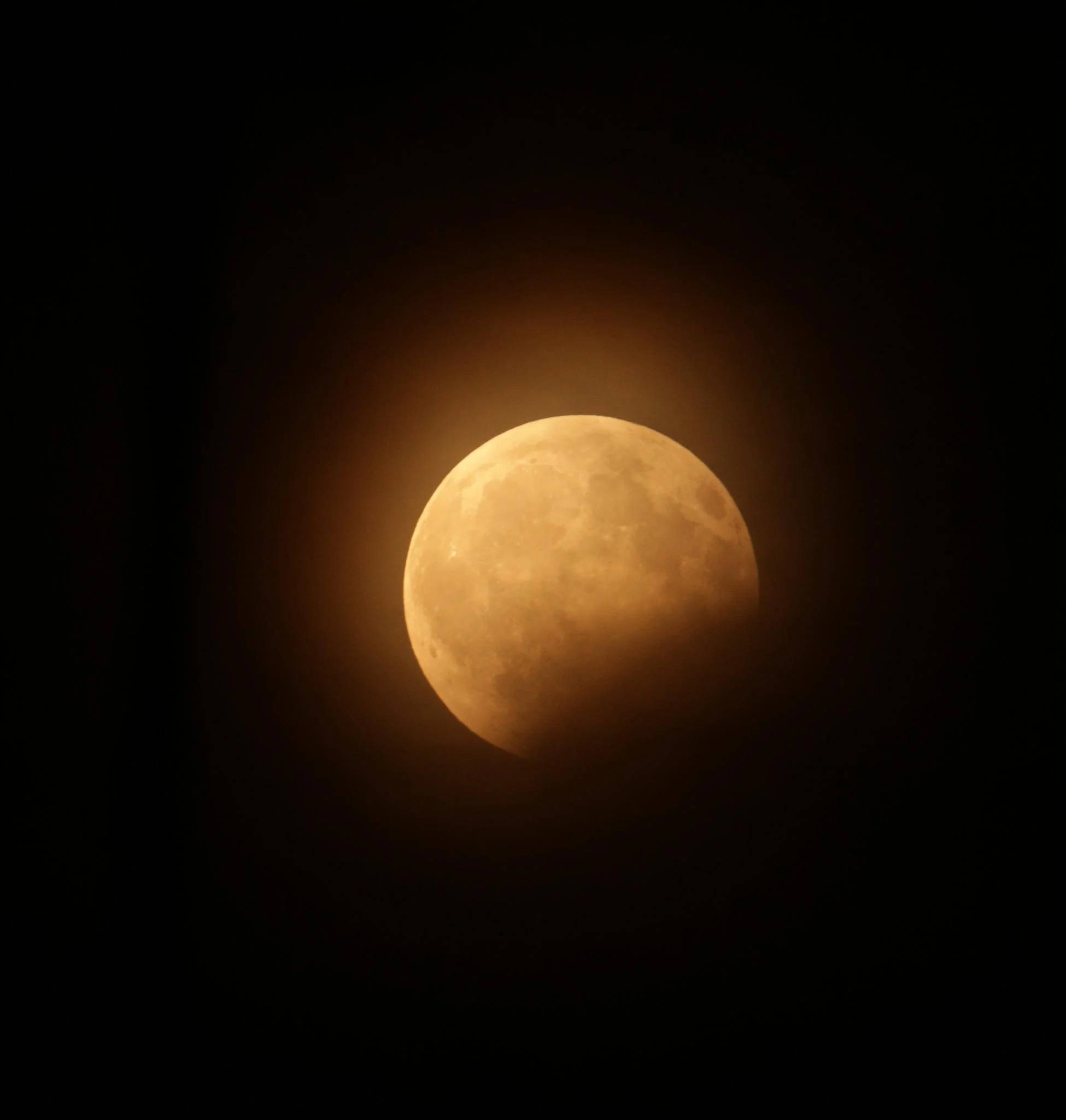 Eclipse 桌布 壁紙 — 一輪發光的琥珀色月亮被陰影部分遮蔽，襯托在深邃的黑色天空中。