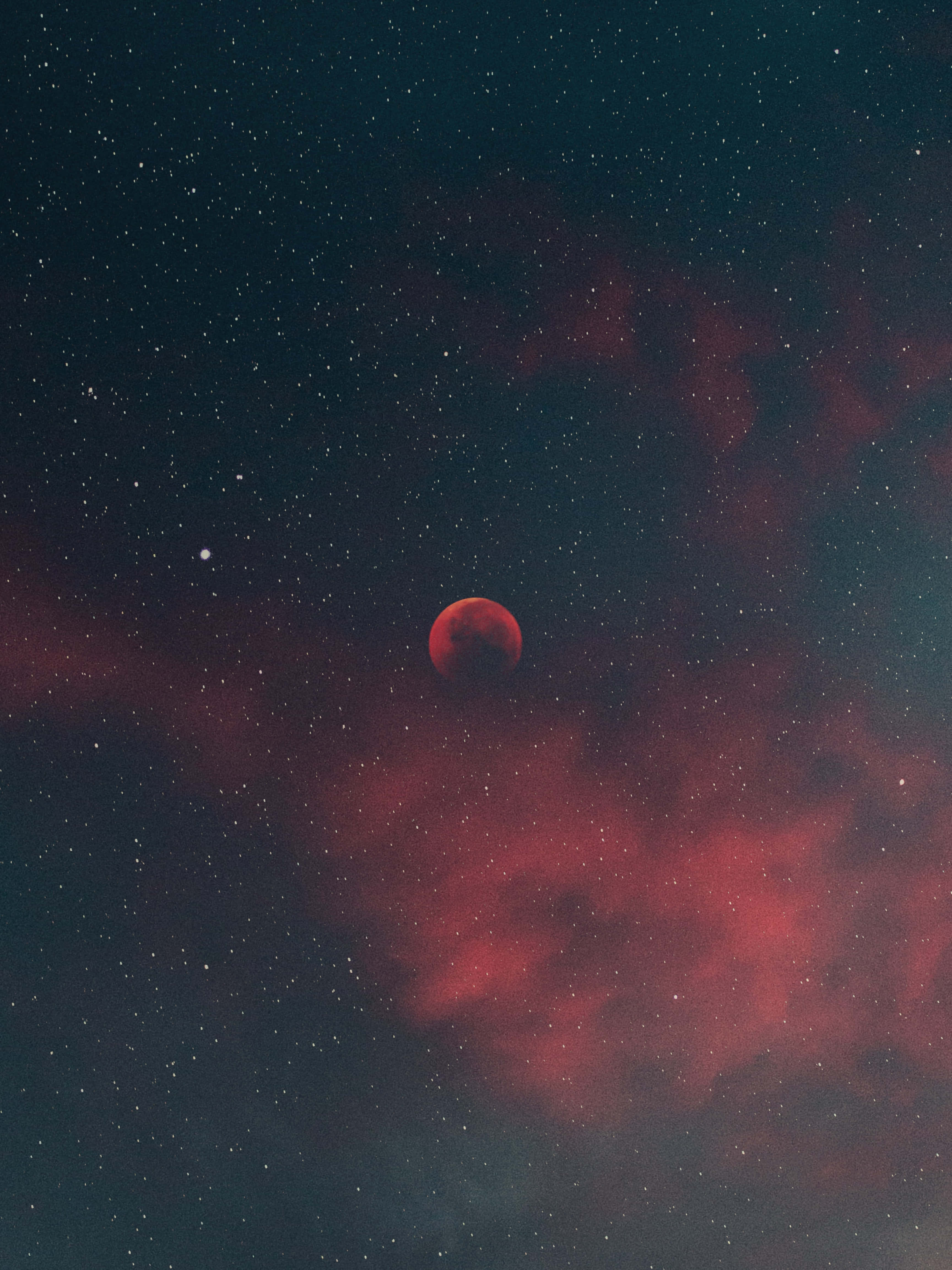 月夜星空 桌布 壁紙 — 一輪血紅色的月亮在旋轉的深紅色星雲和閃爍的星星之間發光，背景是深邃的宇宙夜空。