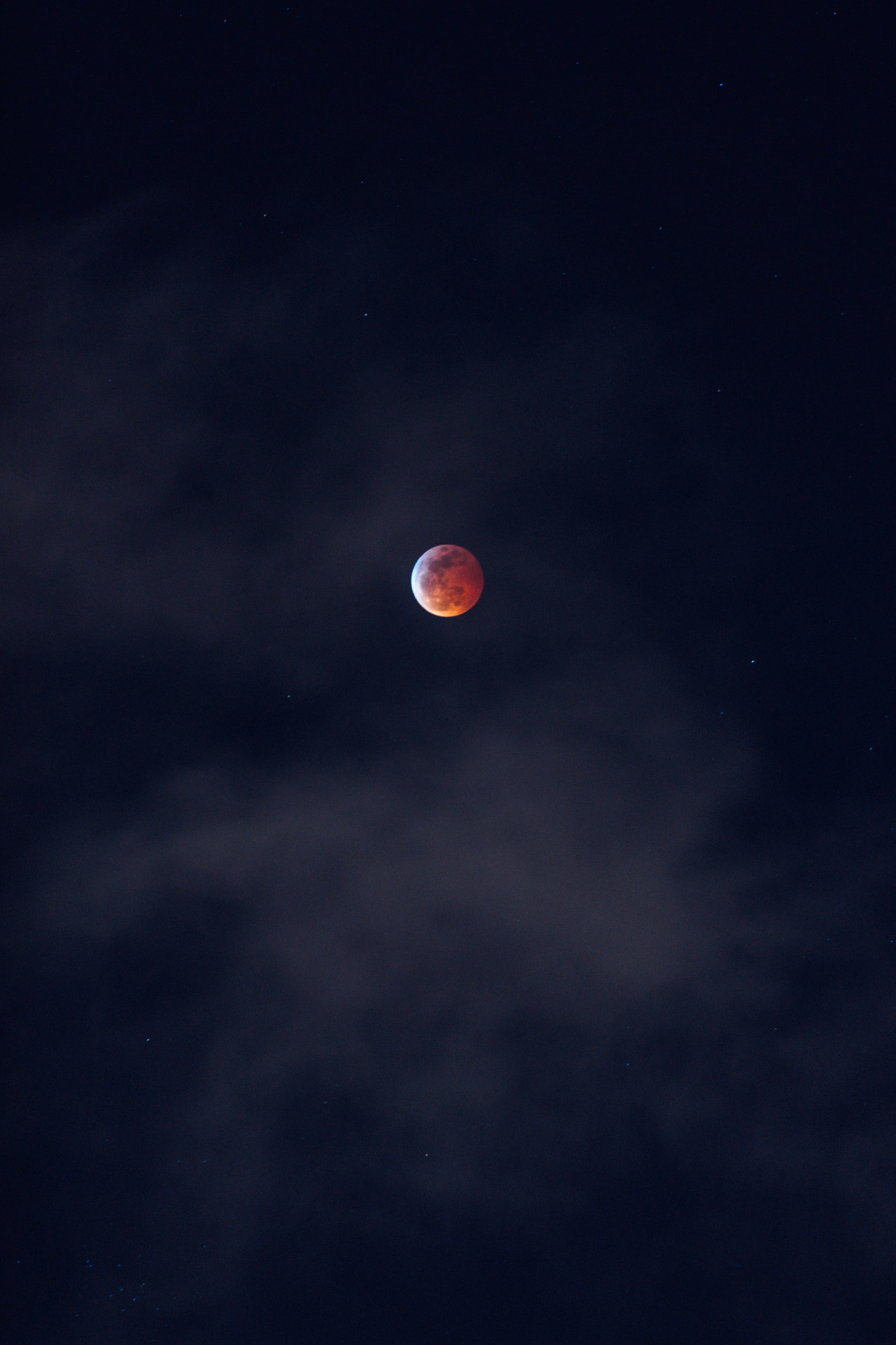 月夜星空 桌布 壁紙 — 一輪血紅色的月亮透過縷縷雲層在繁星點點的夜空中發光。