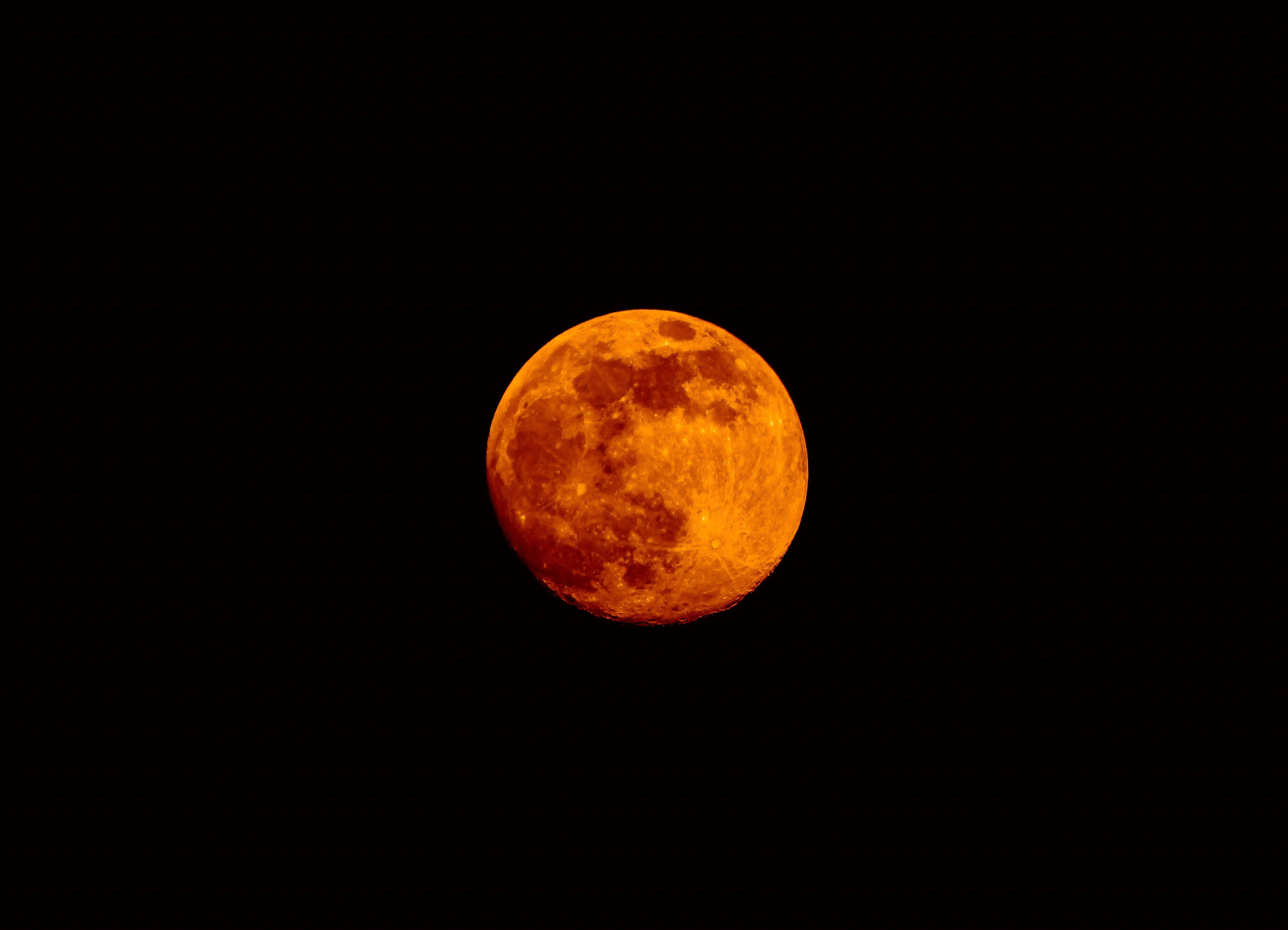 月光 桌布 壁紙 — 一輪鮮豔的橙色滿月在漆黑的夜空中發光，可見隕石坑和月海。