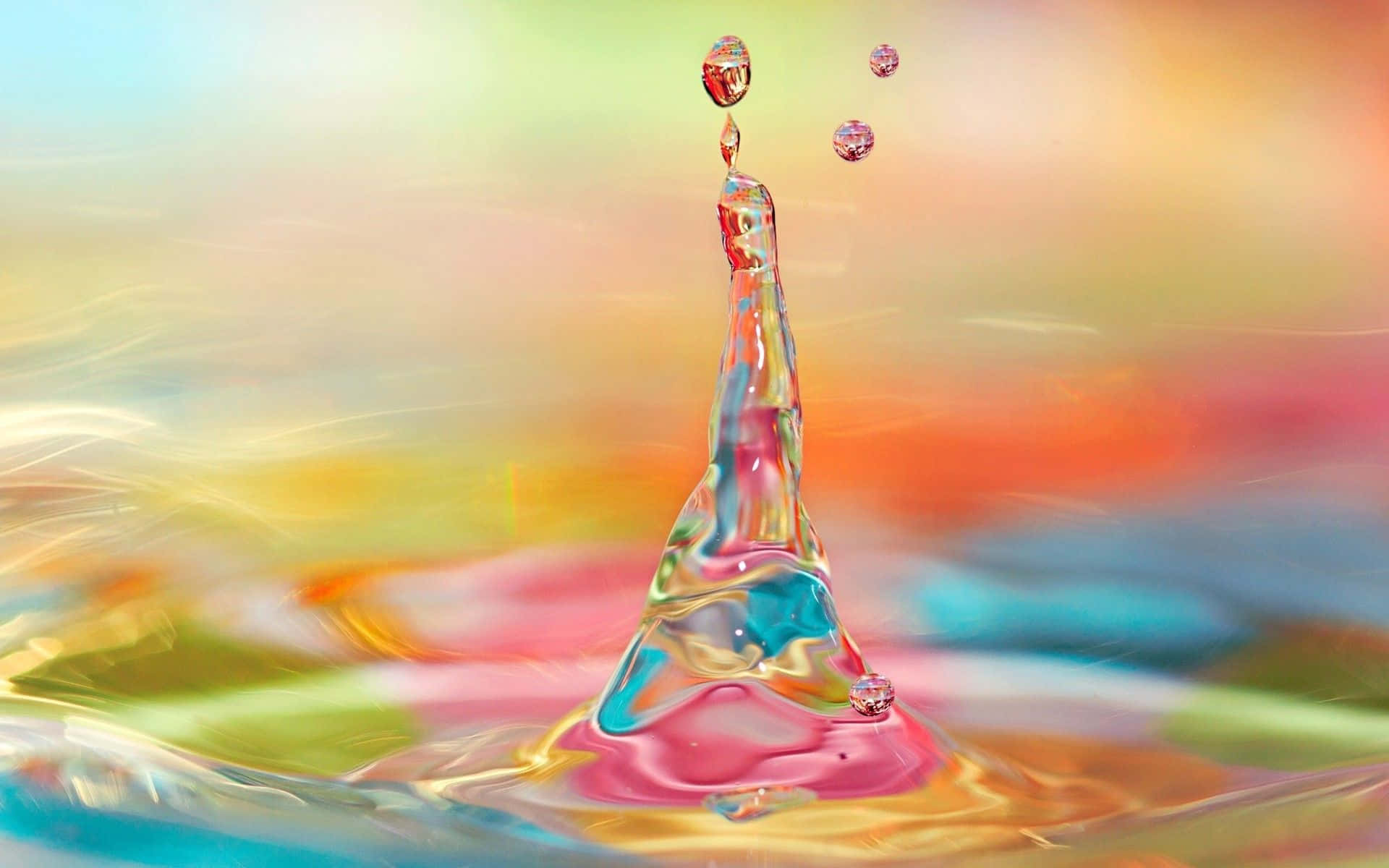 3d Water 桌布 壁紙 — 一道充滿活力的水花形成皇冠形狀，水滴懸浮在半空中，背景是色彩繽紛的模糊效果。