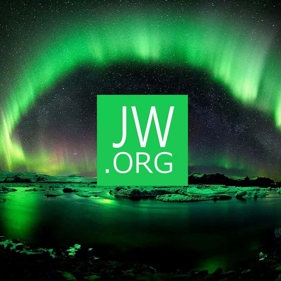 極光 桌布 壁紙 — 一道充滿活力的綠色北極光在繁星點點的夜空上拱起，下方是反射的冰封景觀，並帶有突出的綠色JW.ORG標誌覆蓋層。