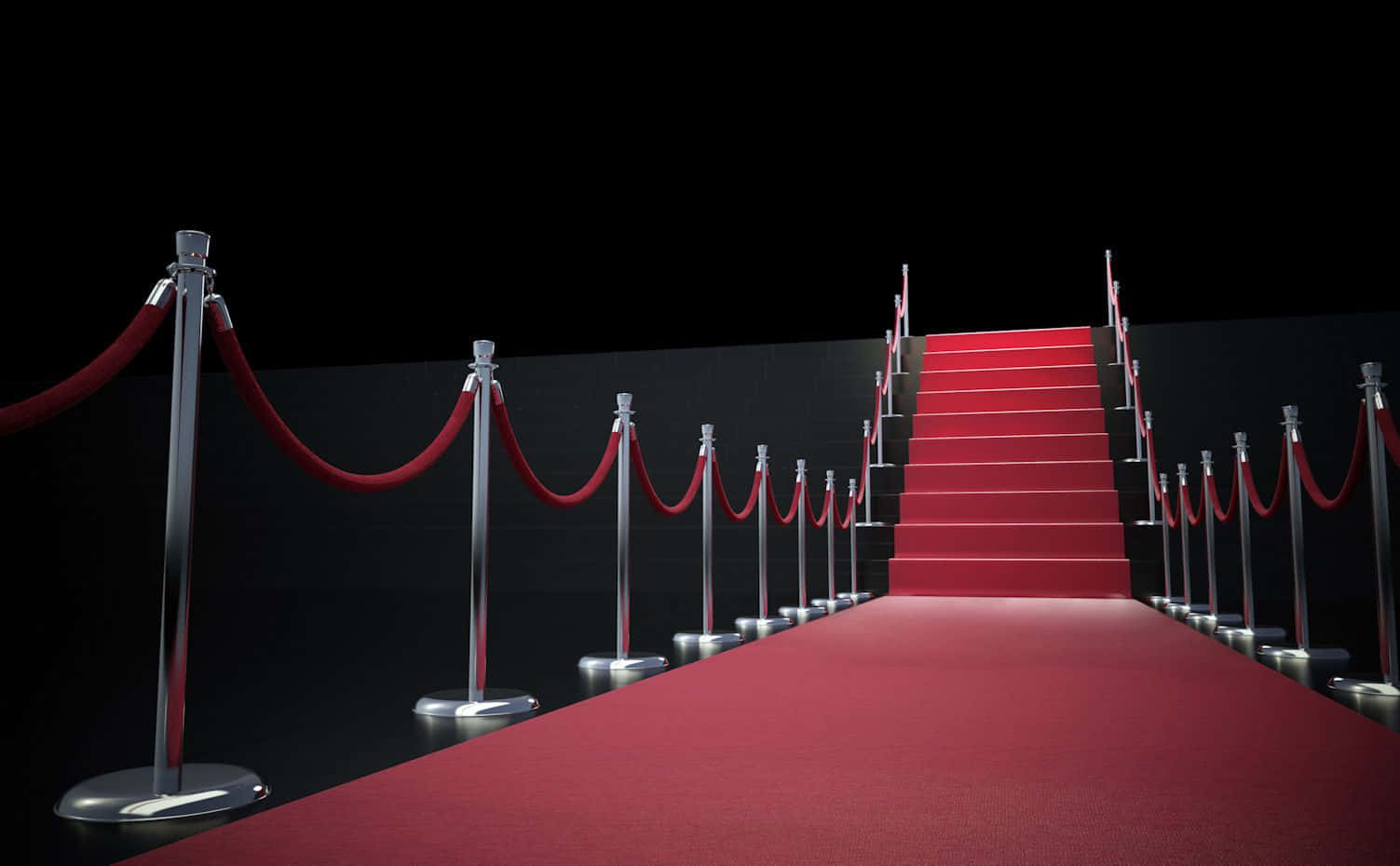 Red Carpet 桌布 壁紙 — 一道光亮的紅地毯樓梯，兩旁有鉻製支柱和天鵝絨繩索，向上延伸至黑暗之中。