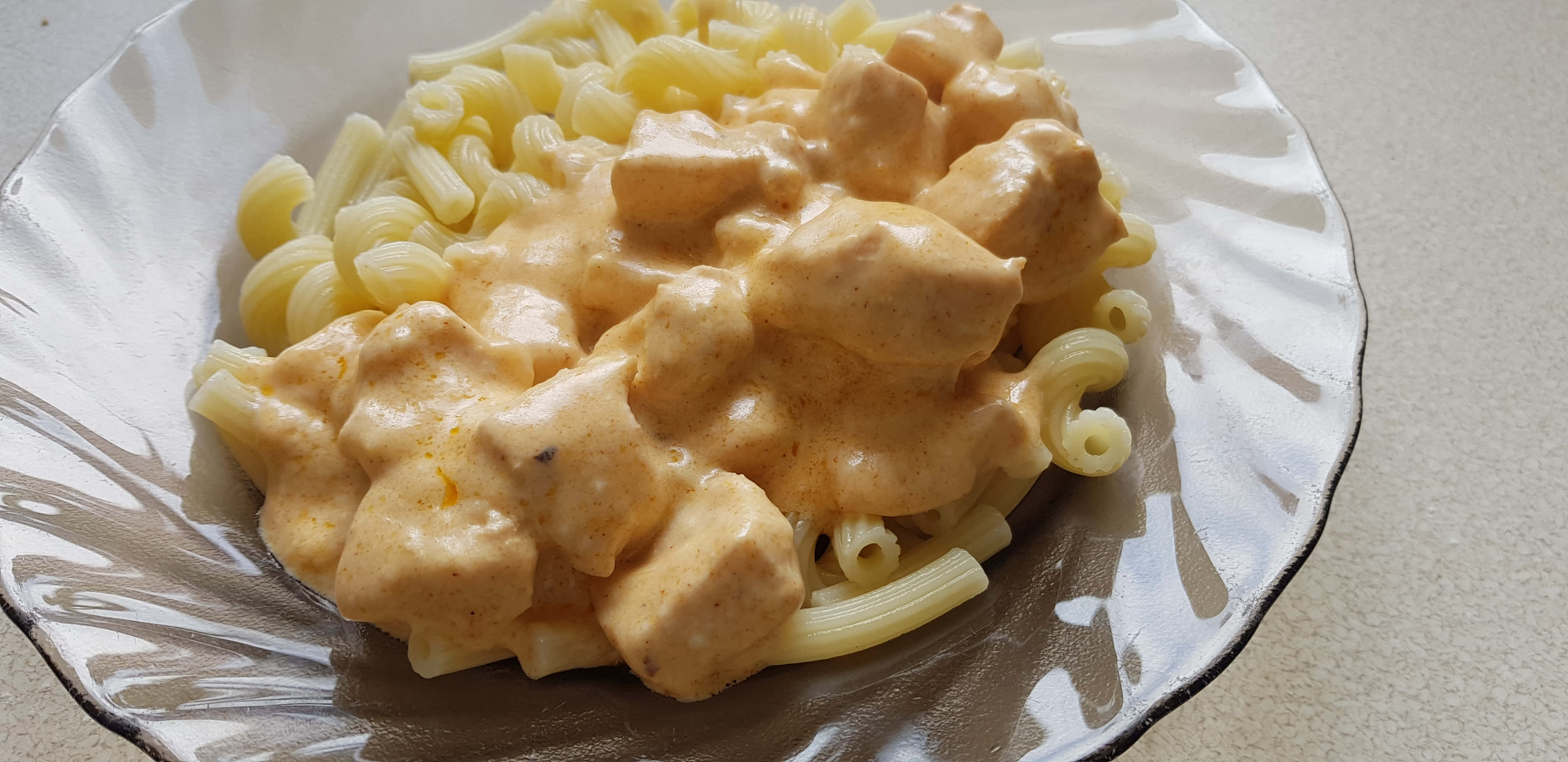 Chicken 桌布 壁紙 — 一道奶油橙雞肉義大利麵，盛裝在白色扇貝邊盤子上，背景為有斑點的檯面。