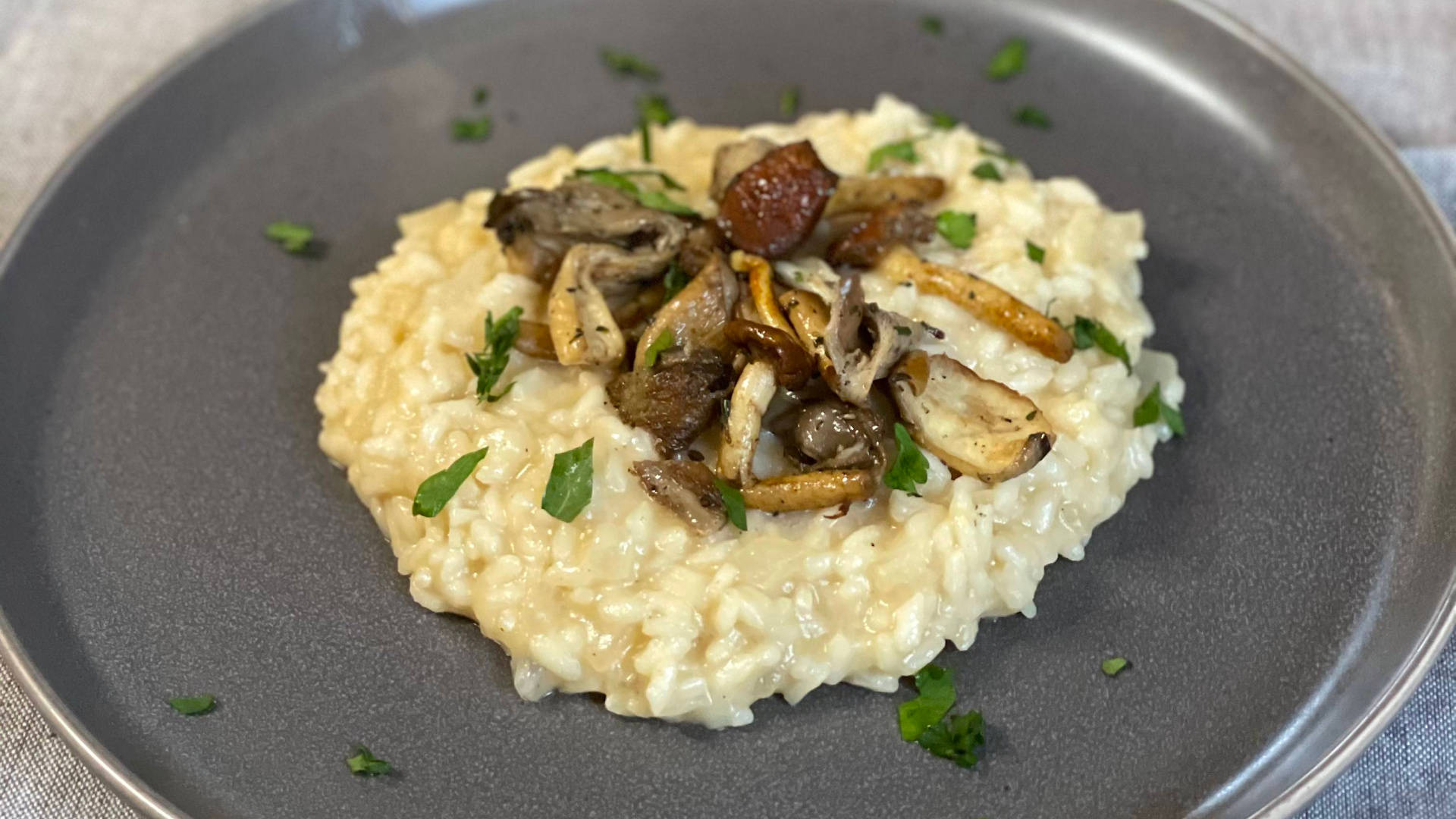 Rice 桌布 壁紙 — 一道奶油蘑菇燴飯，飾以新鮮歐芹，優雅地擺放在磨砂灰色盤子上。