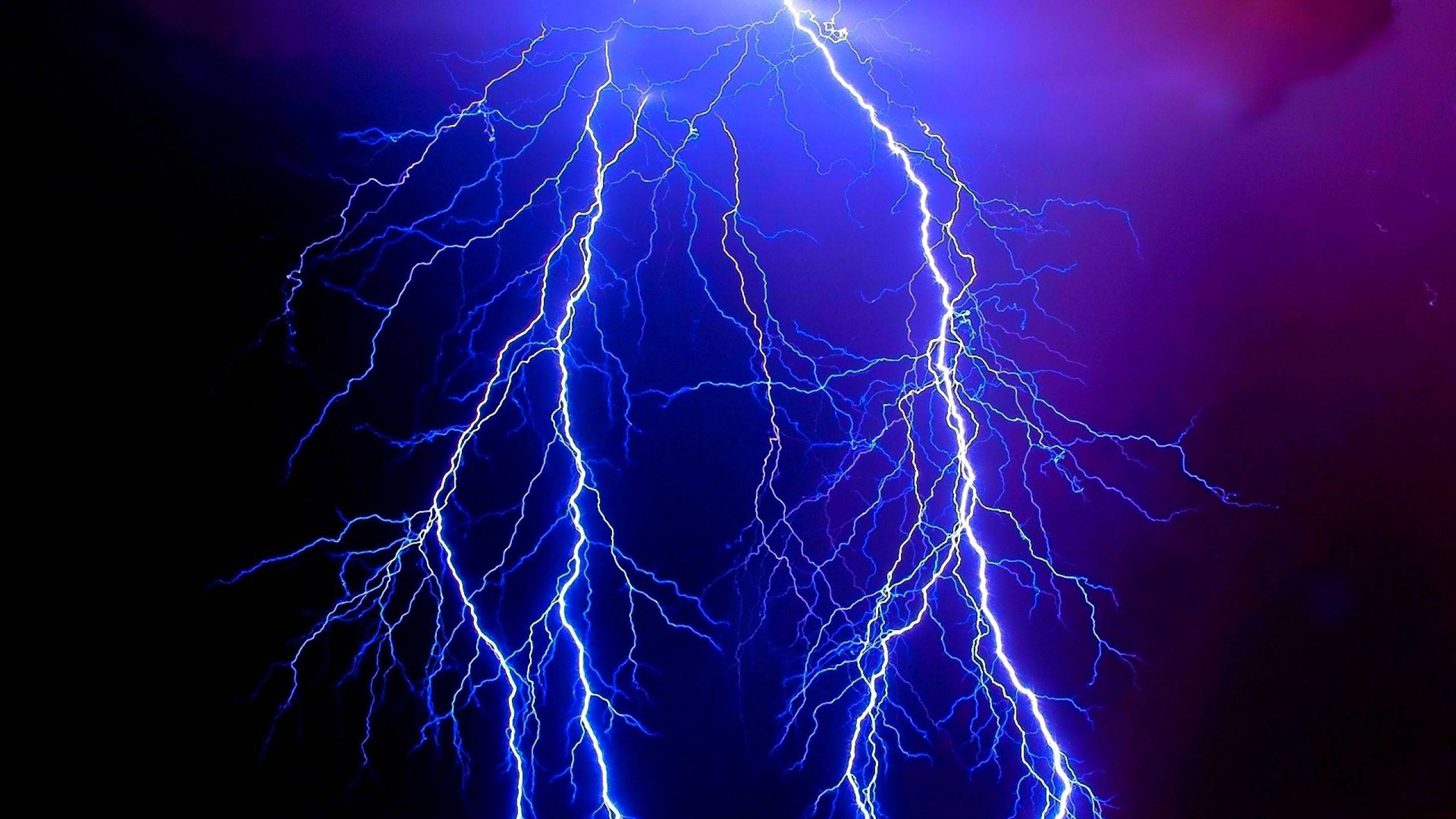 電力 桌布 壁紙 — 一道巨大的藍色閃電在深紫色暴風雨中分叉，形成戲劇性的自然景象。