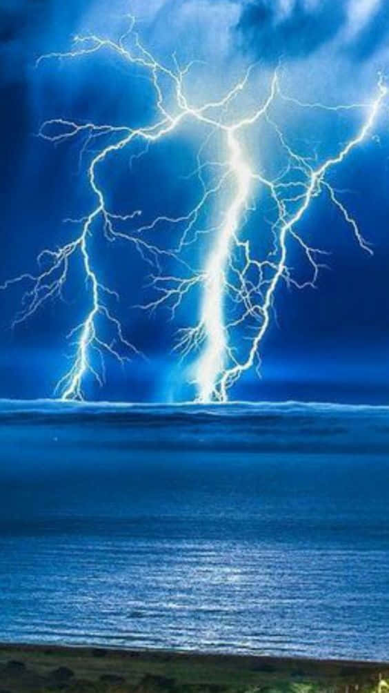 Lightning Bolt iPhone 桌布 壁紙 — 一道巨大的閃電擊中海面，背景是黑暗暴風雨的天空，帶有鮮明的藍色色調。