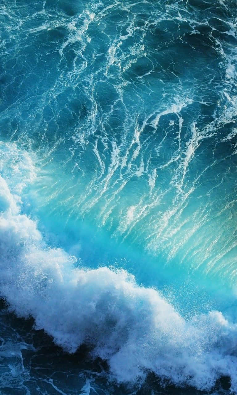 waves 桌布 壁紙 — 一道強勁的海浪向上衝擊，呈現鮮豔的藍綠色和白色泡沫，映襯著較深的藍色海洋。