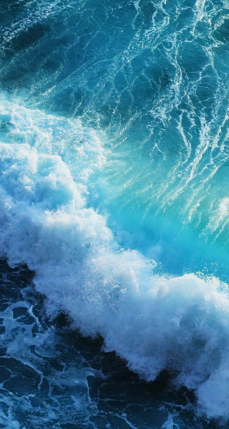 Blue iPhone Xr 桌布 壁紙 — 一道強勁的海浪拍打著深藍色的海水，激起白色泡沫，呈現動態的特寫鏡頭。