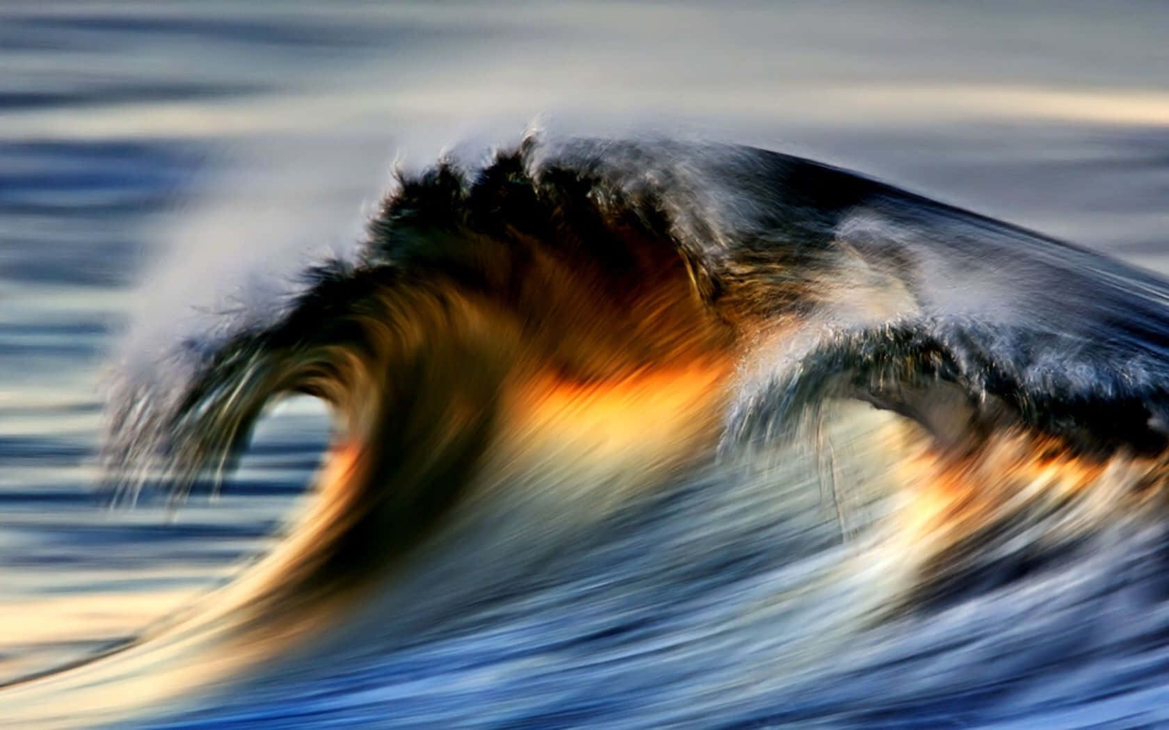 Ocean Waves 桌布 壁紙 — 一道強勁的海浪捲起，帶有動態模糊效果，金色光線穿過浪尖，映襯著柔和的藍色海洋。